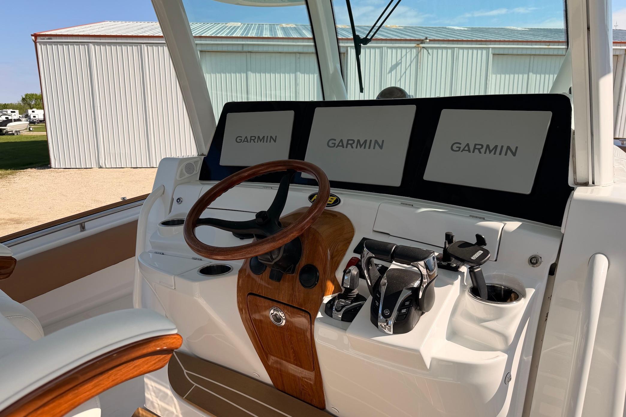 Helm of 2022 HCB 42 Lujo boat with Garmin displays and wooden steering wheel.