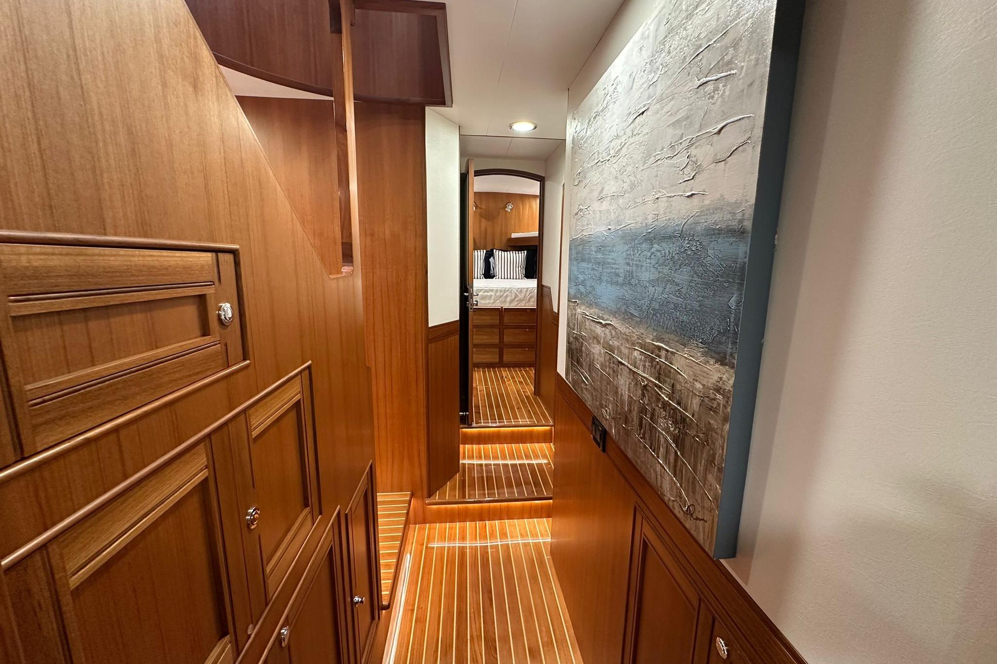 Luxurious interior hallway of 2023 Marlow Explorer 66E-CB yacht with wood paneling and artwork.