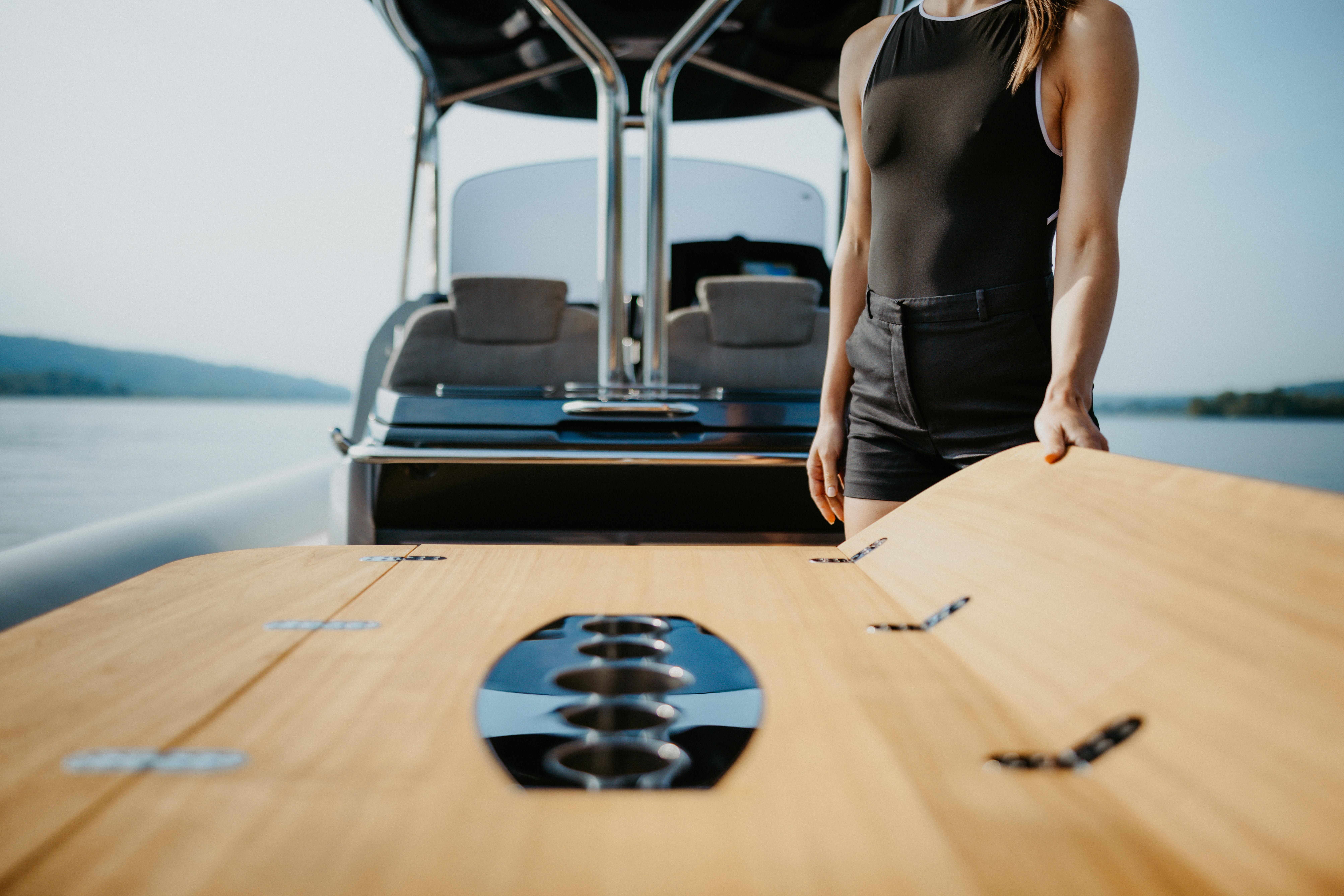 2026 SACS Strider 11 yacht with a woman adjusting a wooden table on deck.