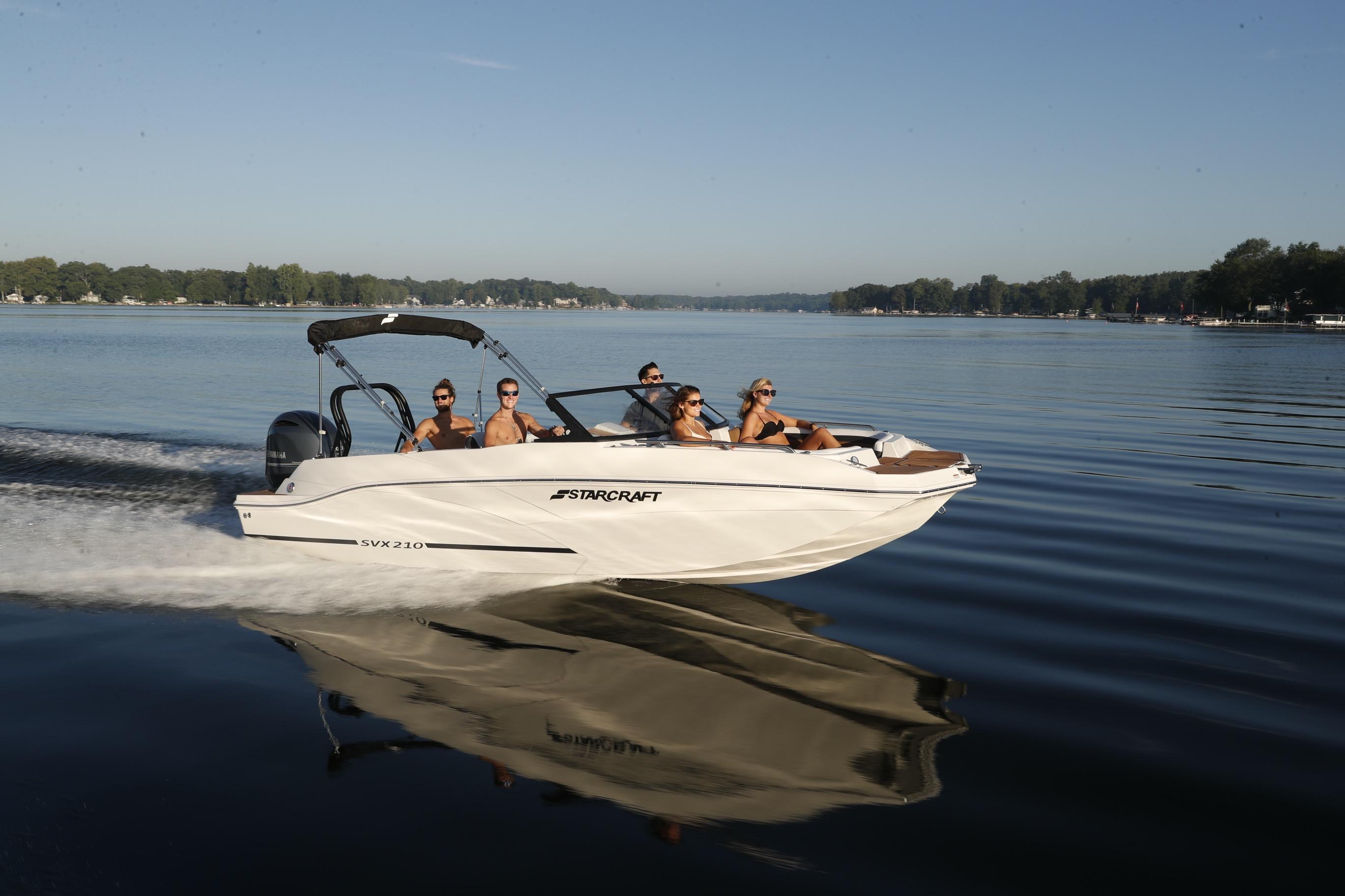 2026 Starcraft SVX 210 DC OB boat cruising on a serene lake with passengers.