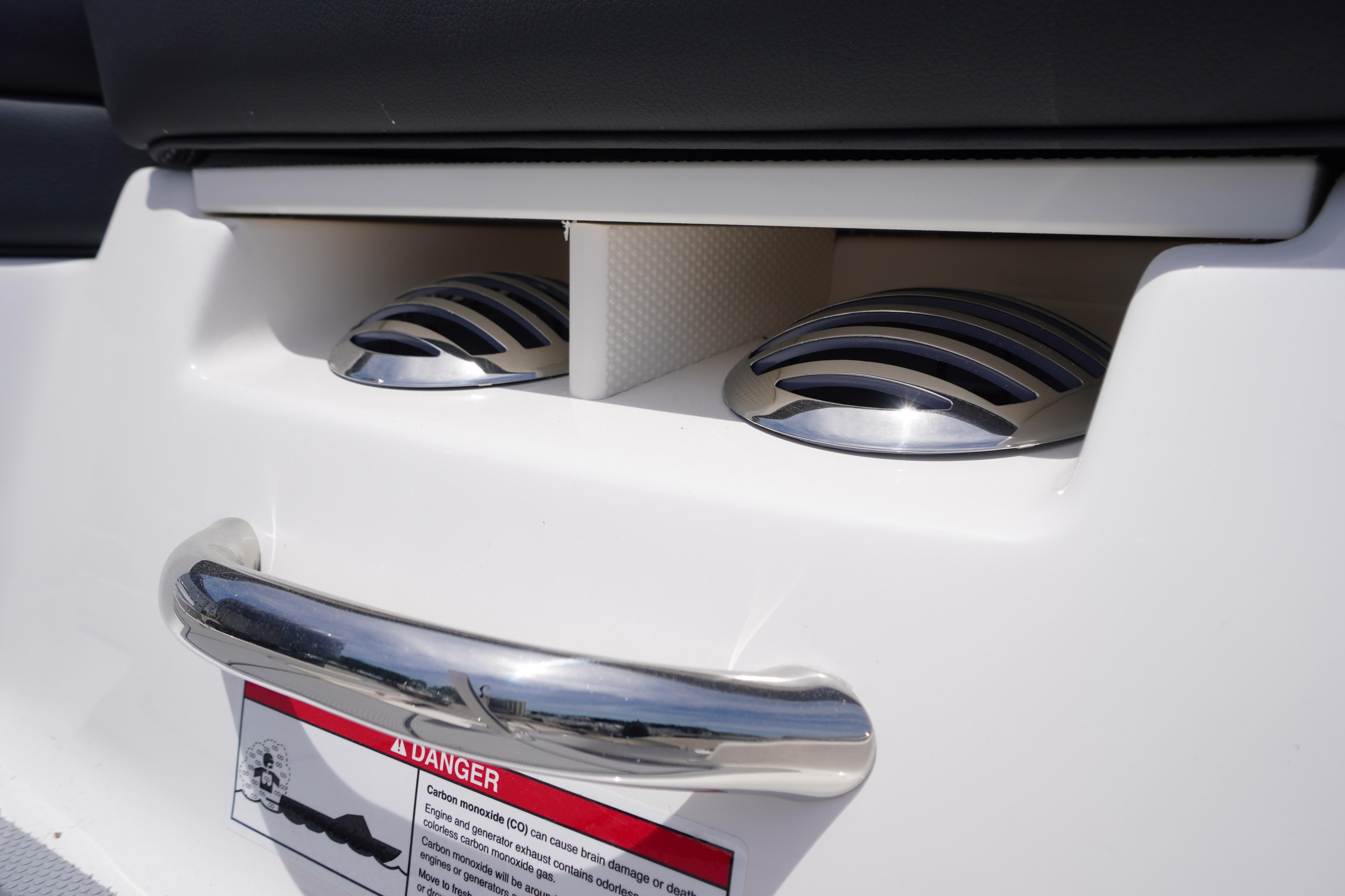 2026 Chaparral 23 SSi OB boat detail with chrome accents and safety warning label.