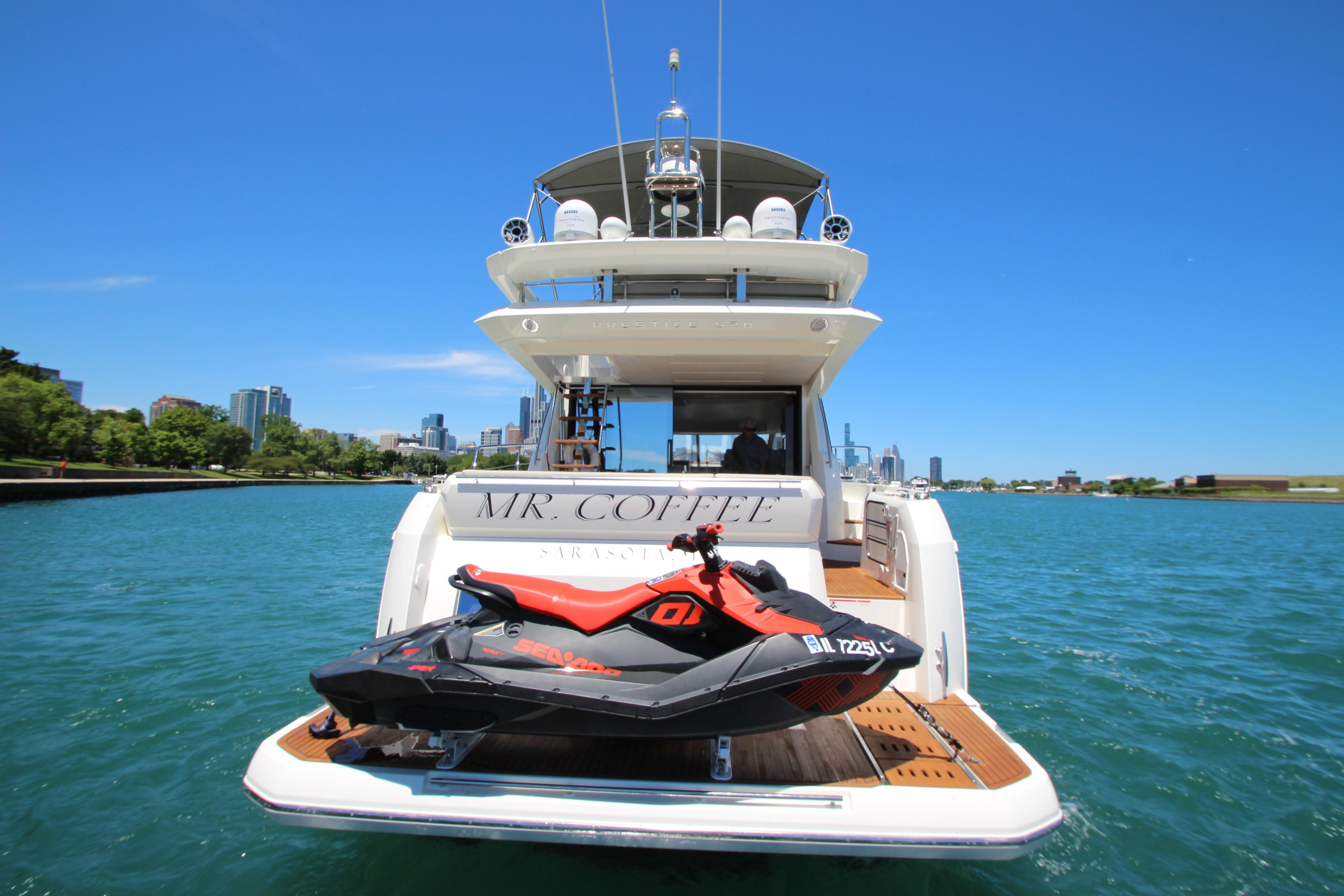 2022 Prestige 520 yacht with jet ski on deck, city skyline in background.