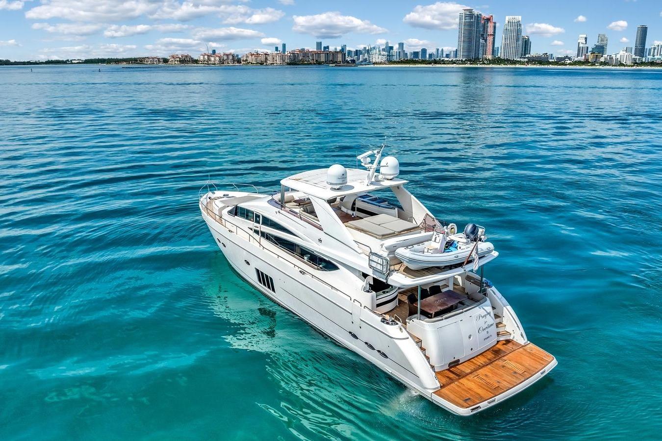 Luxurious 2012 Princess 85 yacht cruising in clear blue waters near a city skyline.