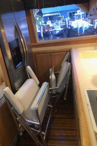 Interior of a 1997 Bertram Convertible yacht with folded chairs and a stainless steel refrigerator.