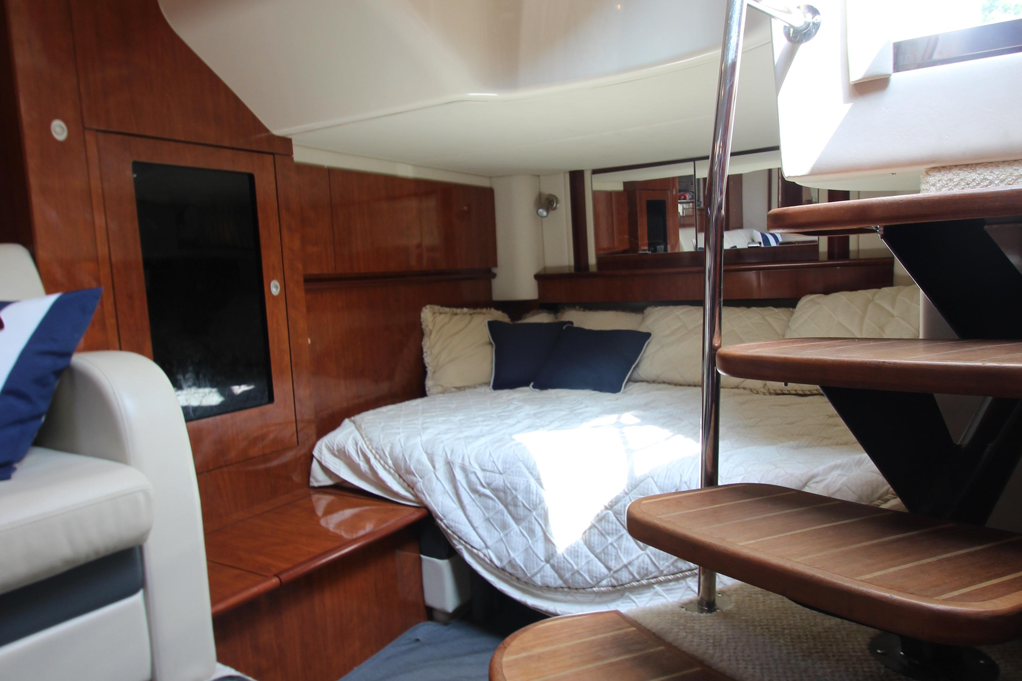 Luxurious interior of 2004 Sea Ray 40 Sundancer yacht with cozy bed and wooden stairs.
