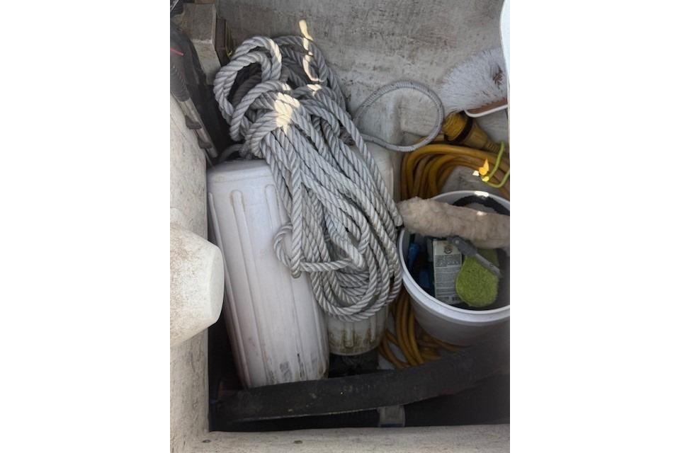 Storage compartment on a 2002 Beneteau First 36.7 with ropes, fender, and cleaning supplies.