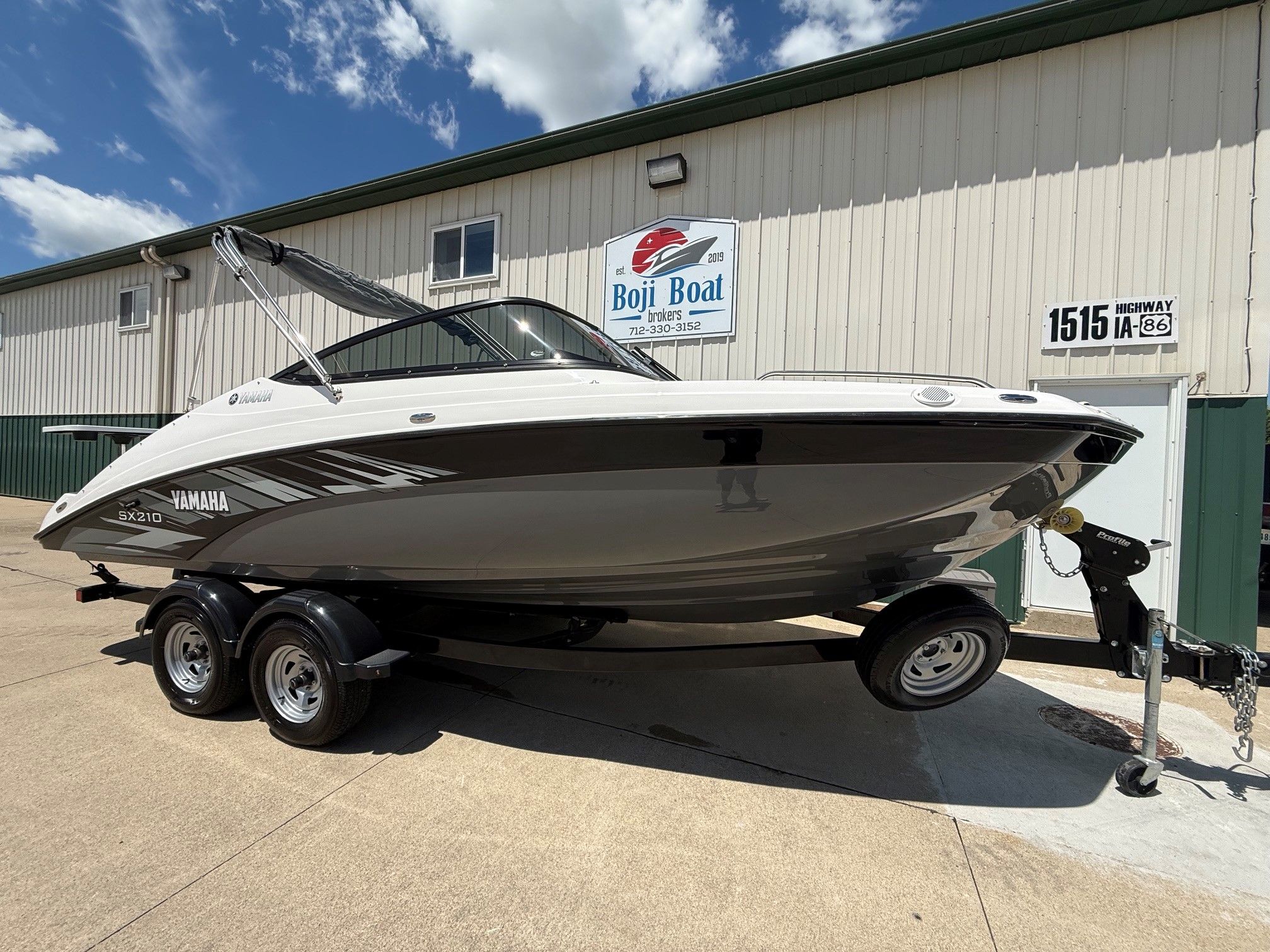 A Yamaha SX210 boat on a trailer in front of a building.