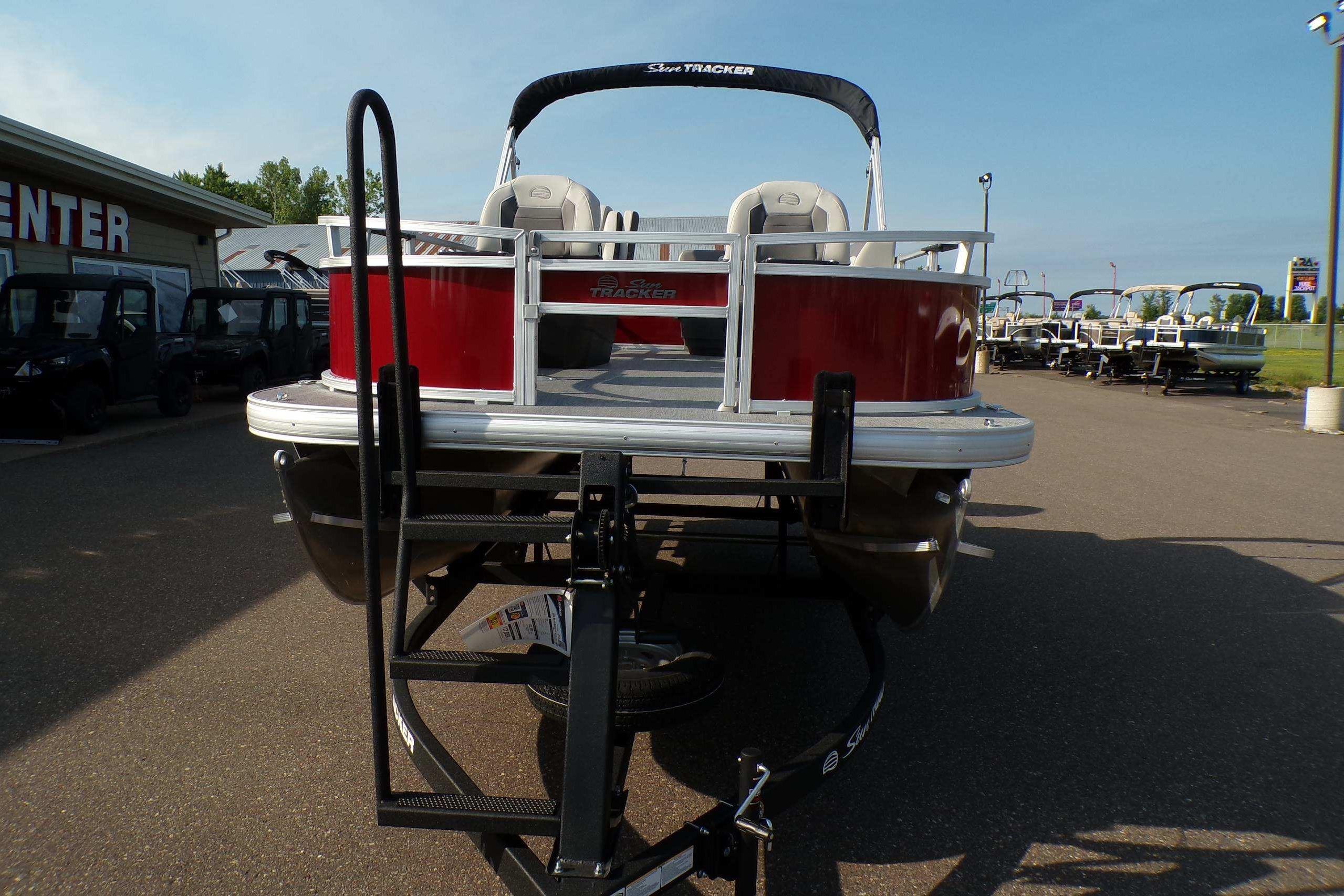 2026 Sun Tracker Bass Buggy 16 XL Select pontoon boat on trailer, parked outdoors.