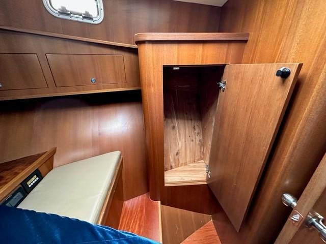 Cozy wooden cabin interior of 2025 Bracewell 41 boat with open storage.