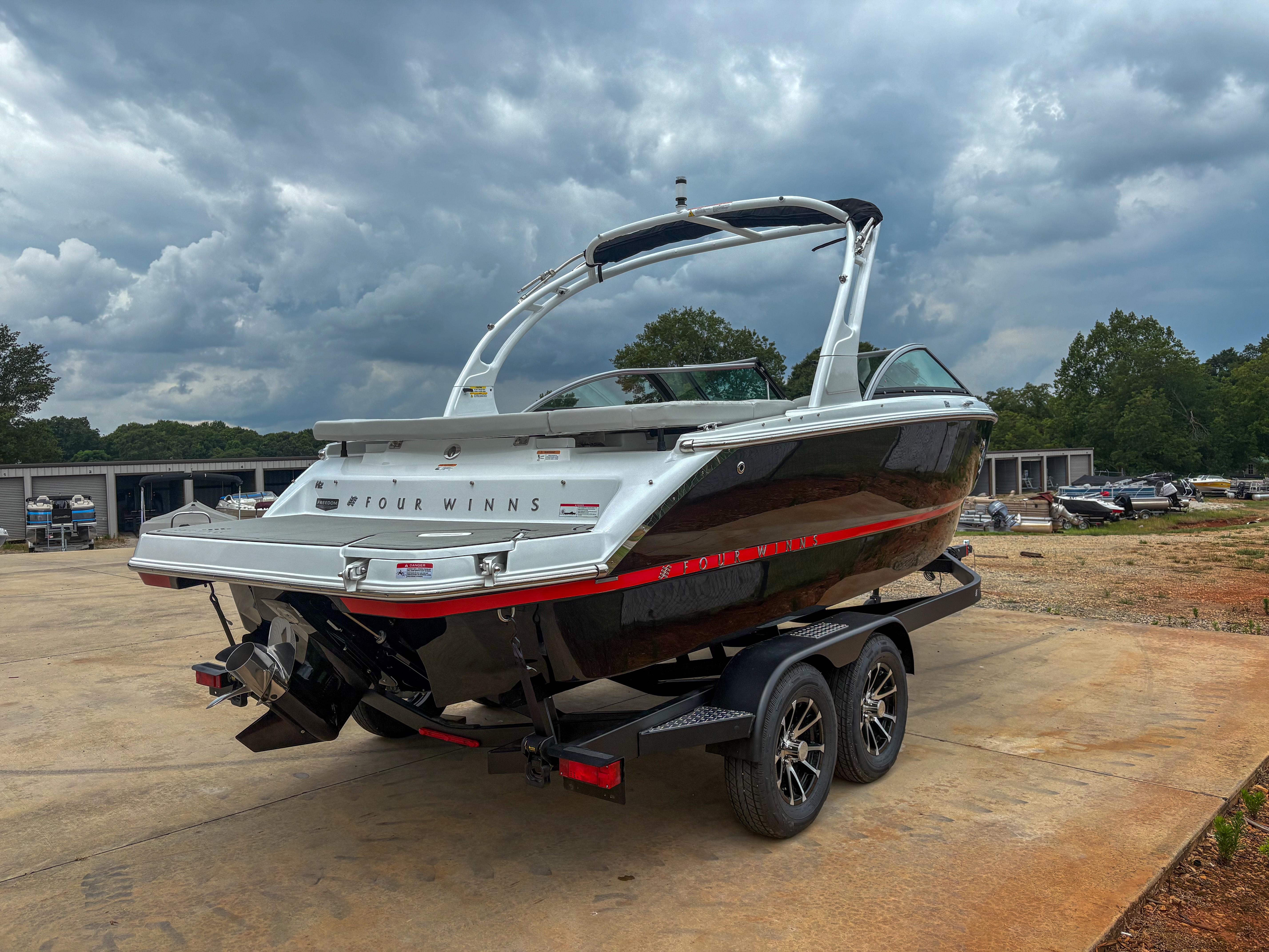2026 Four Winns H2 Freedom boat on trailer under cloudy sky.