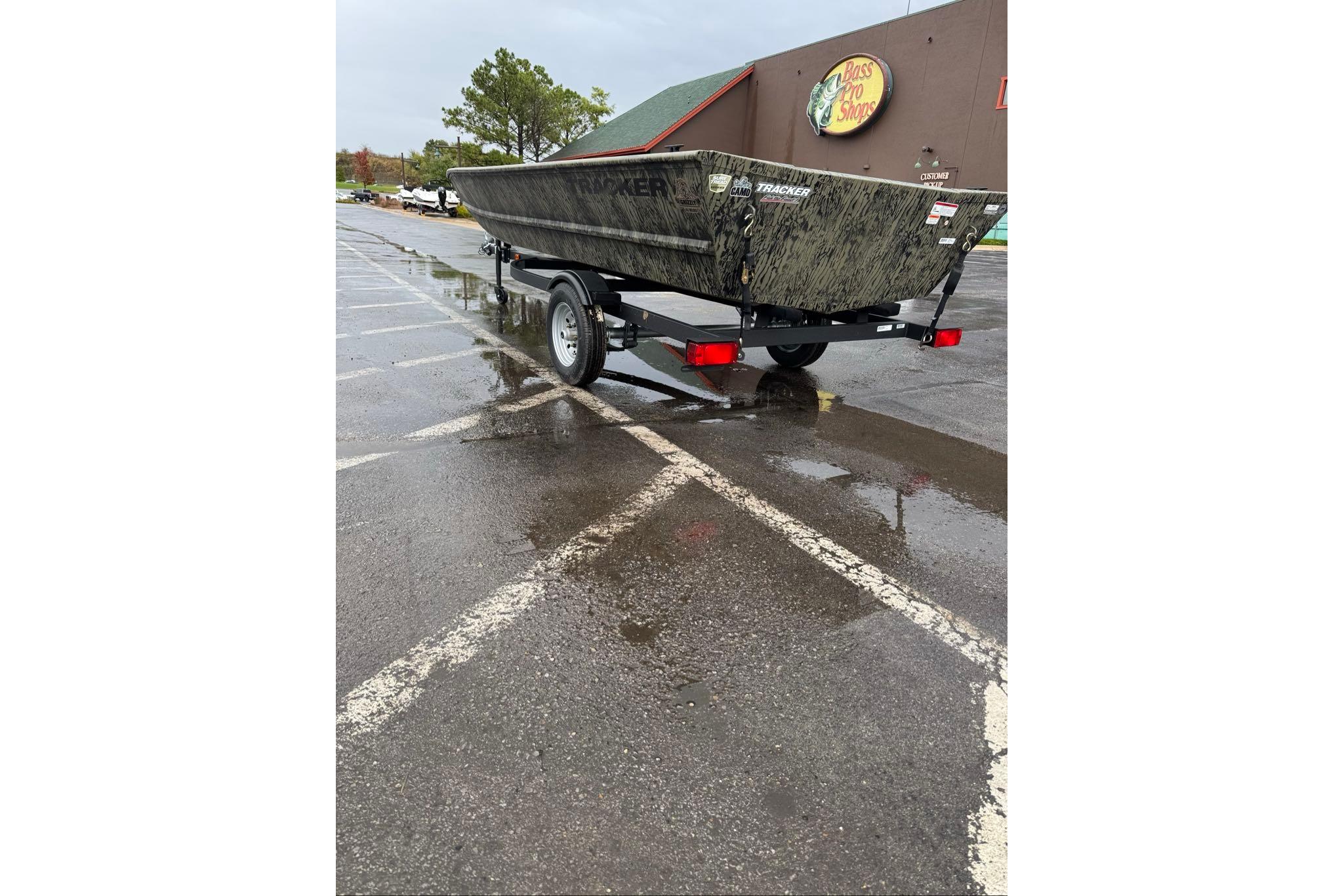 2026 Tracker Grizzly 1648 Utility boat on trailer in wet parking lot.