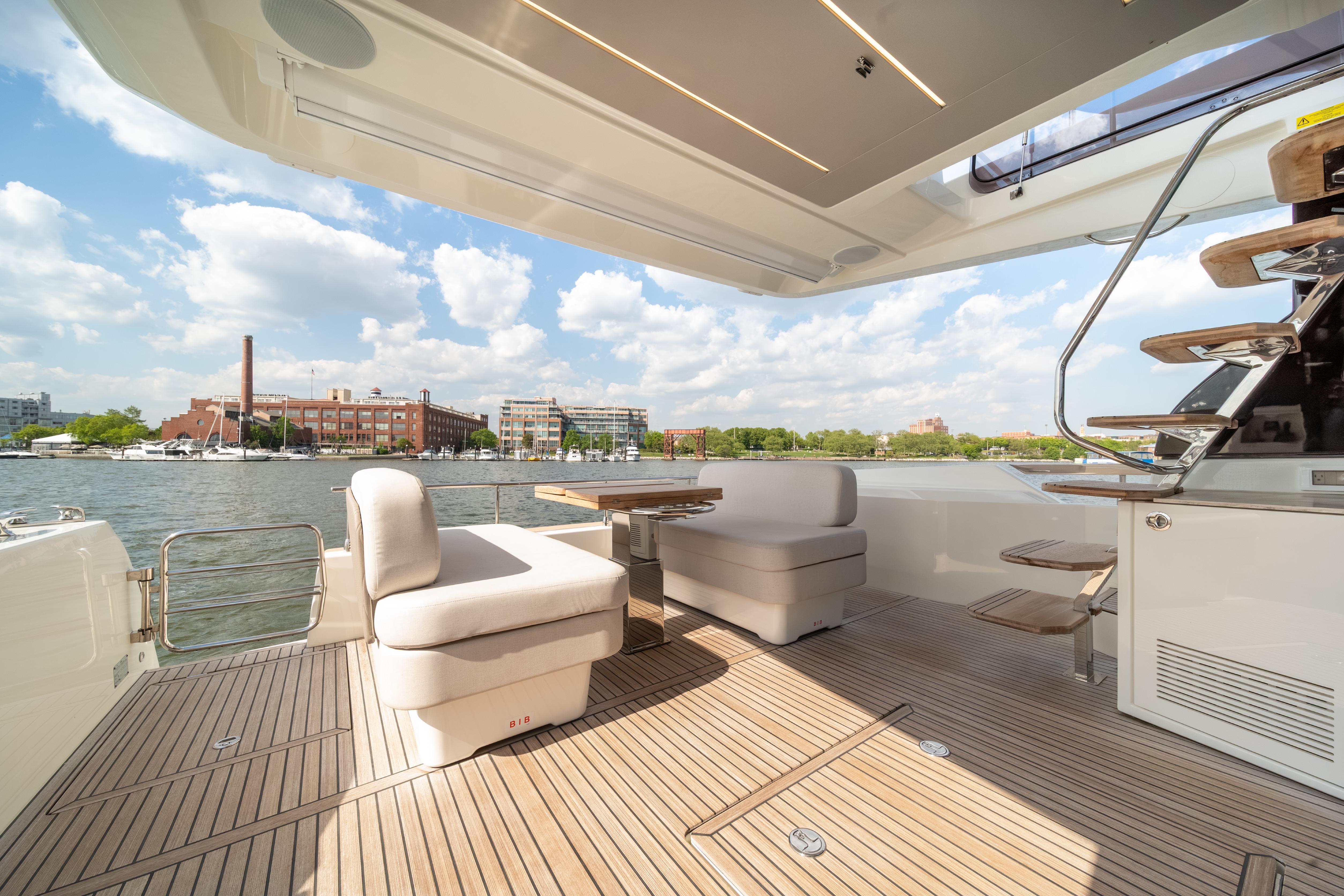 Luxurious Prestige F4.9 yacht deck with seating, overlooking waterfront cityscape, 2025 model.