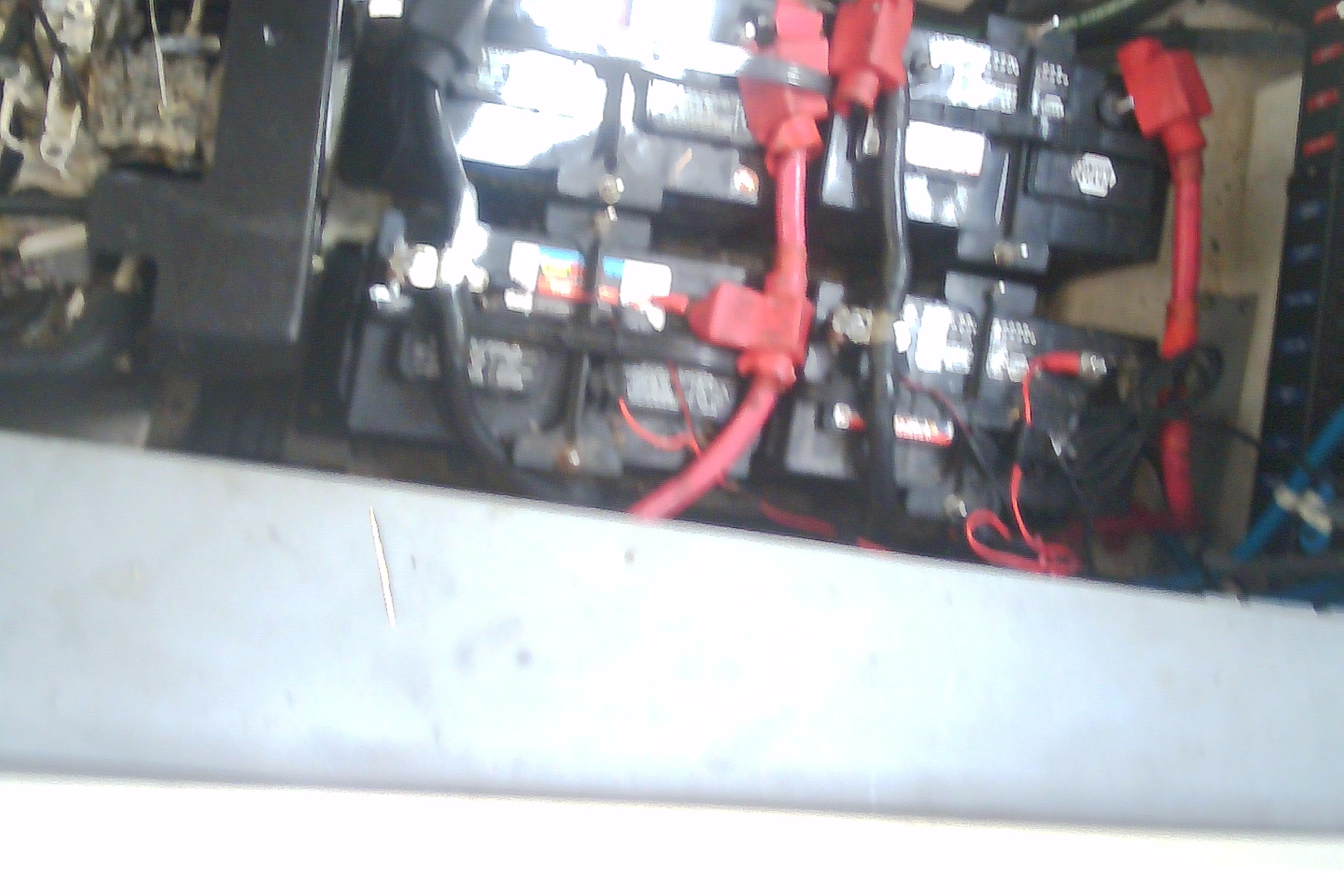 Battery compartment of a 2005 Sea Ray 300 Sundancer with red cables.
