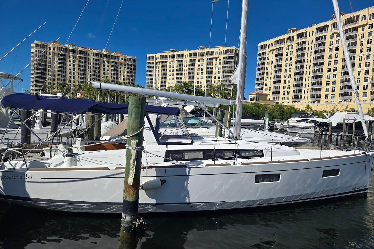 2023 Beneteau Oceanis 38.1 sailboat docked at marina with tall buildings in background.