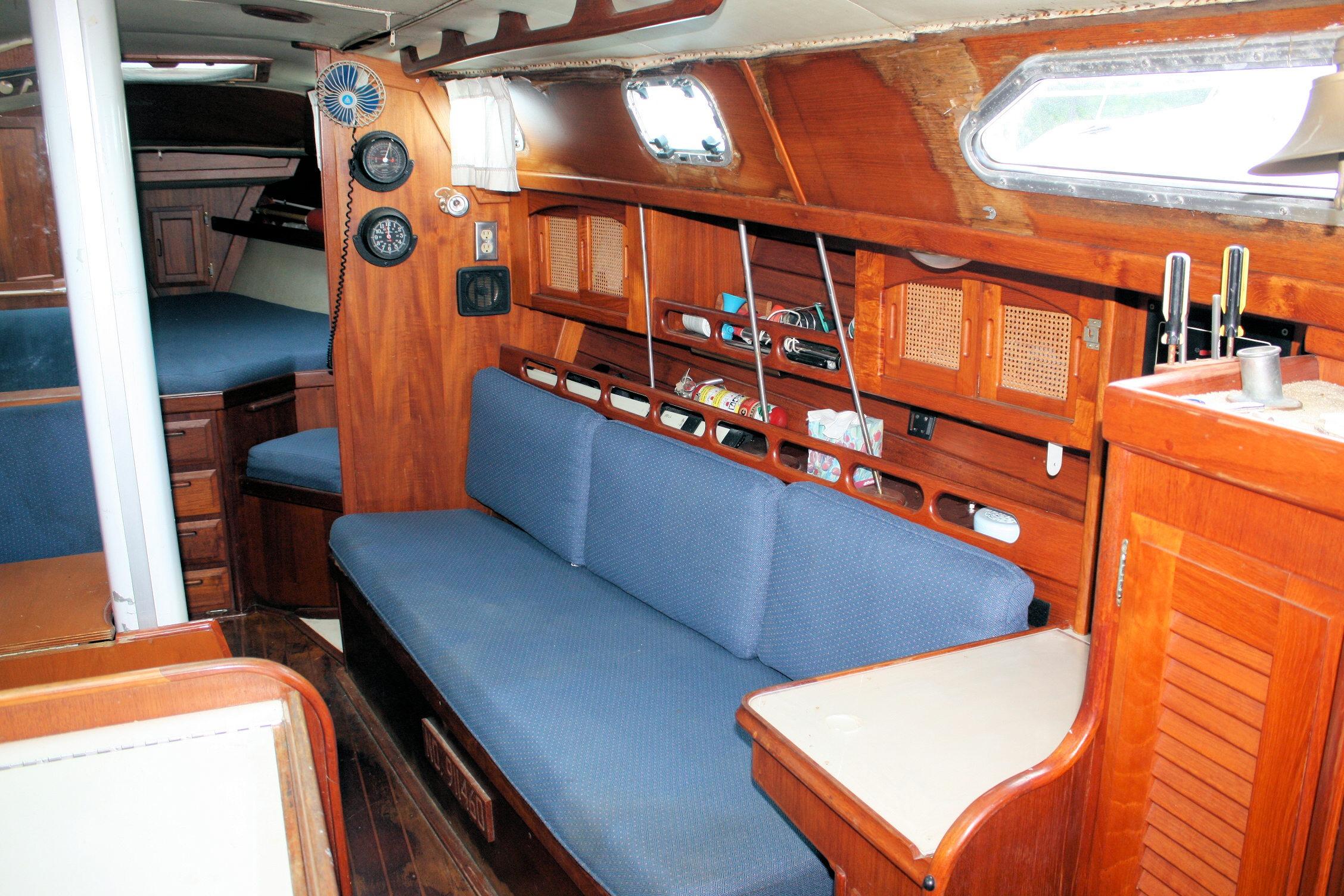 Interior of 1987 Ericson 38-200 sailboat with wooden cabinetry and blue seating.