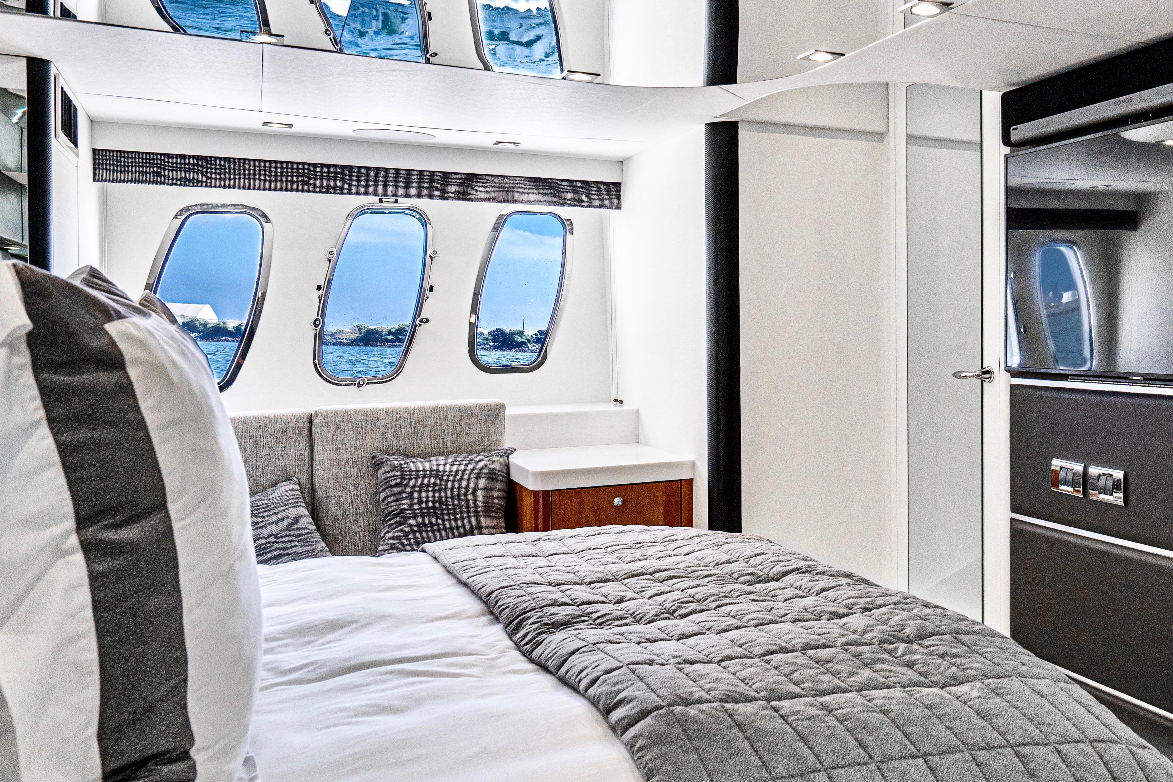Luxurious bedroom interior of 2021 Sunseeker Predator 68 yacht with ocean view windows.