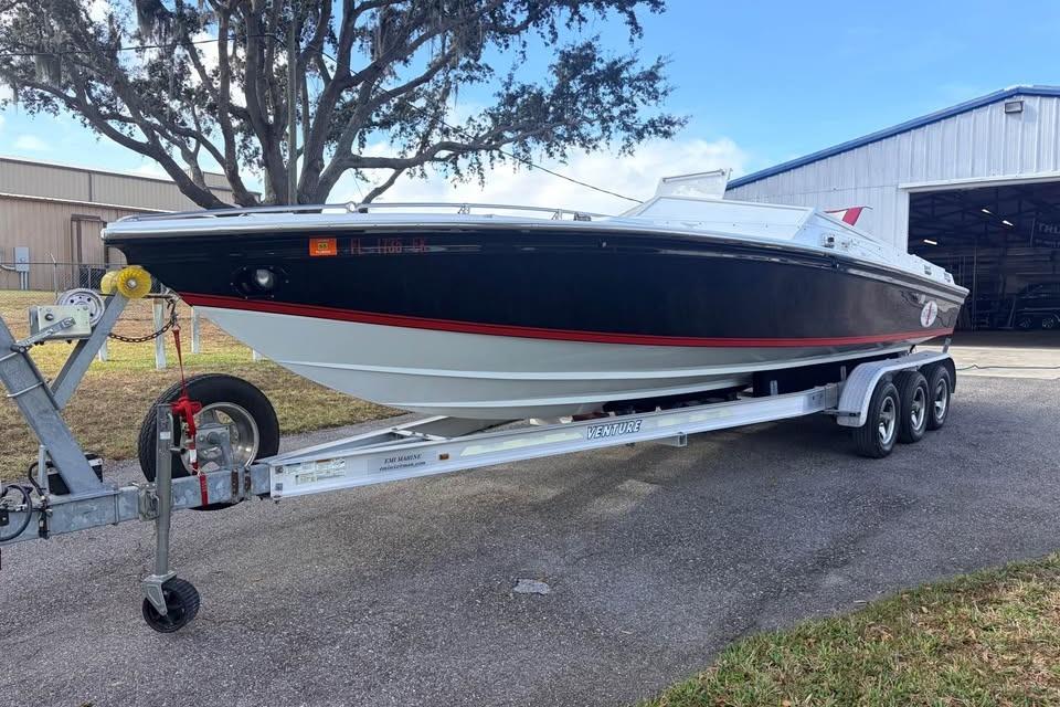 1983 Cigarette 24' Classic boat on trailer, parked outdoors near a warehouse.