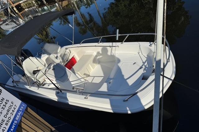 2024 Boston Whaler 160 SS boat docked on calm water with canopy and seating.