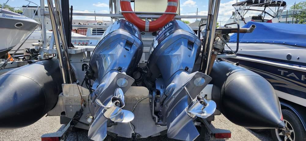 Twin outboard motors on a 2006 Airsolid 26 Dive Boat, docked with other vessels.