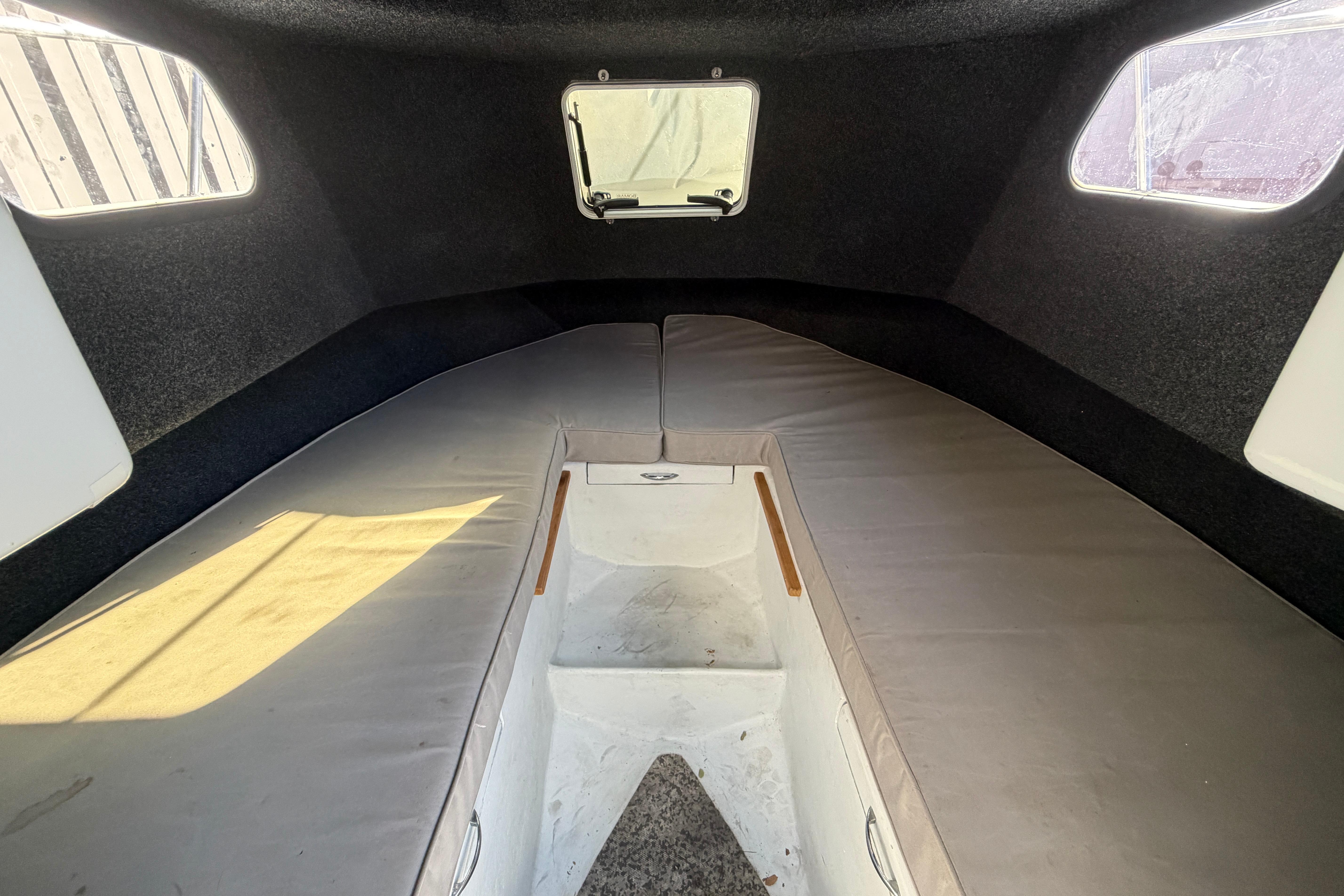 Interior cabin of a 1986 Radon 21 Sport boat, featuring cushioned seating and windows.