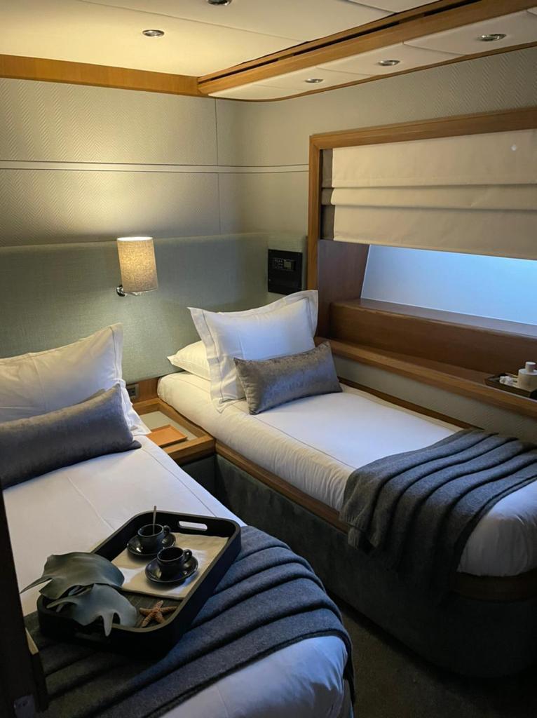 Luxurious twin cabin on 2003 Azimut 98 Leonardo yacht, featuring elegant bedding and modern decor.