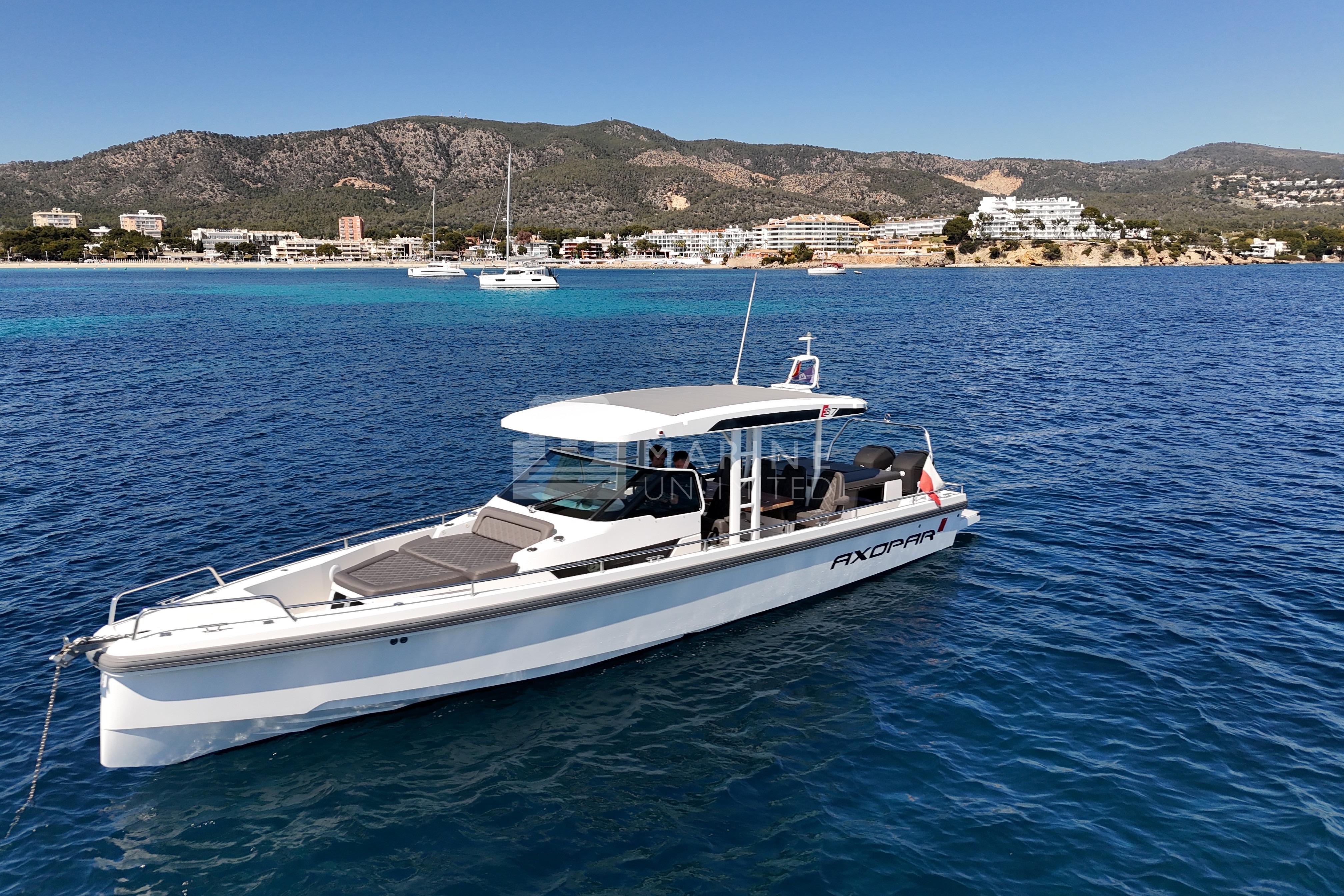 2016 Axopar 37 Sun-Top boat on clear blue water near scenic coastline.