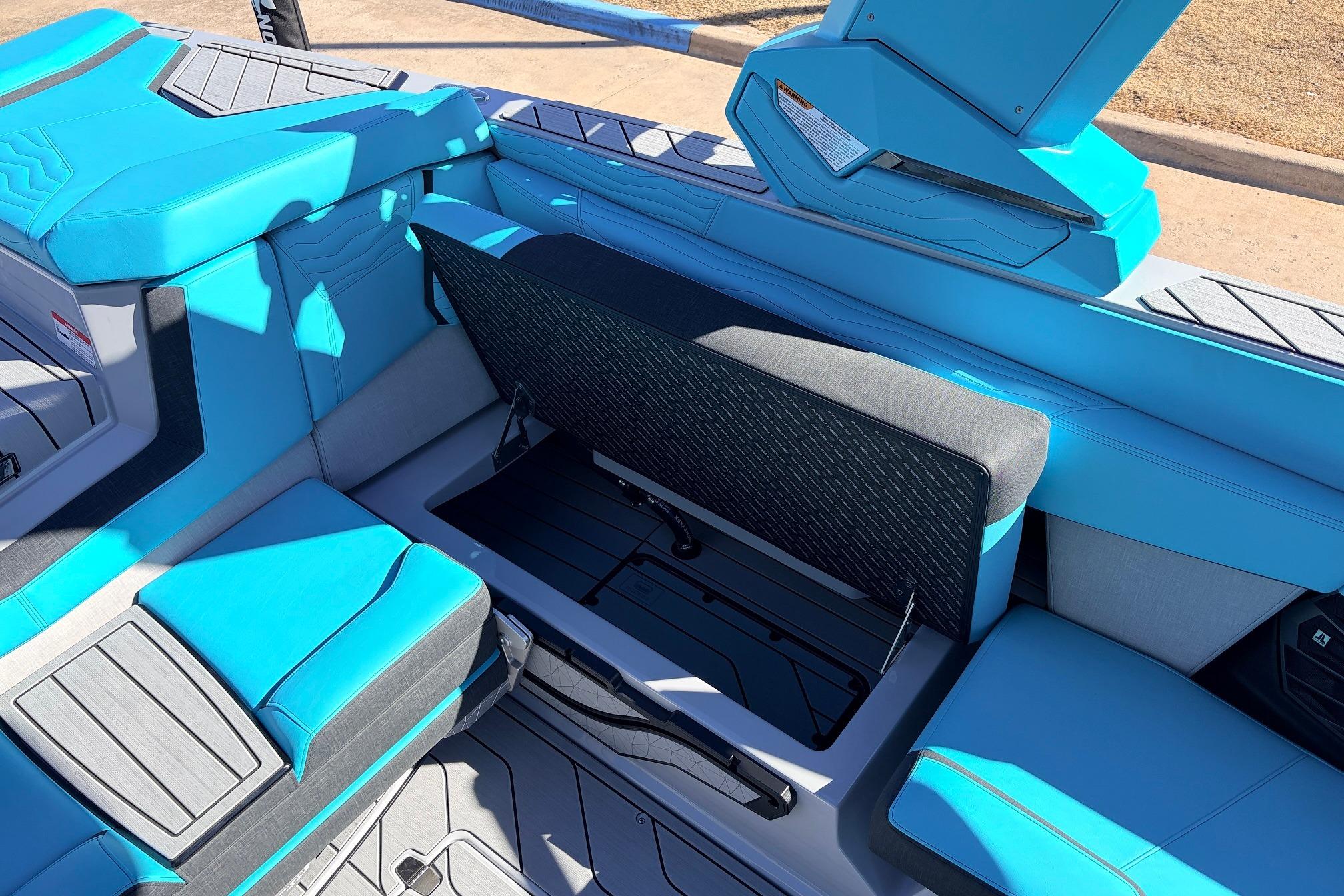 2026 Nautique Super Air Nautique G23 interior with blue seating and open storage compartment.