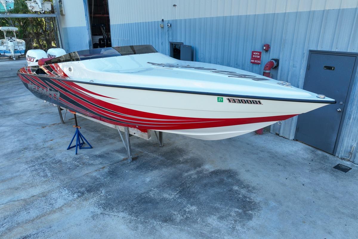 2022 Velocity 290sc speedboat with red and white design, parked on concrete near a building.