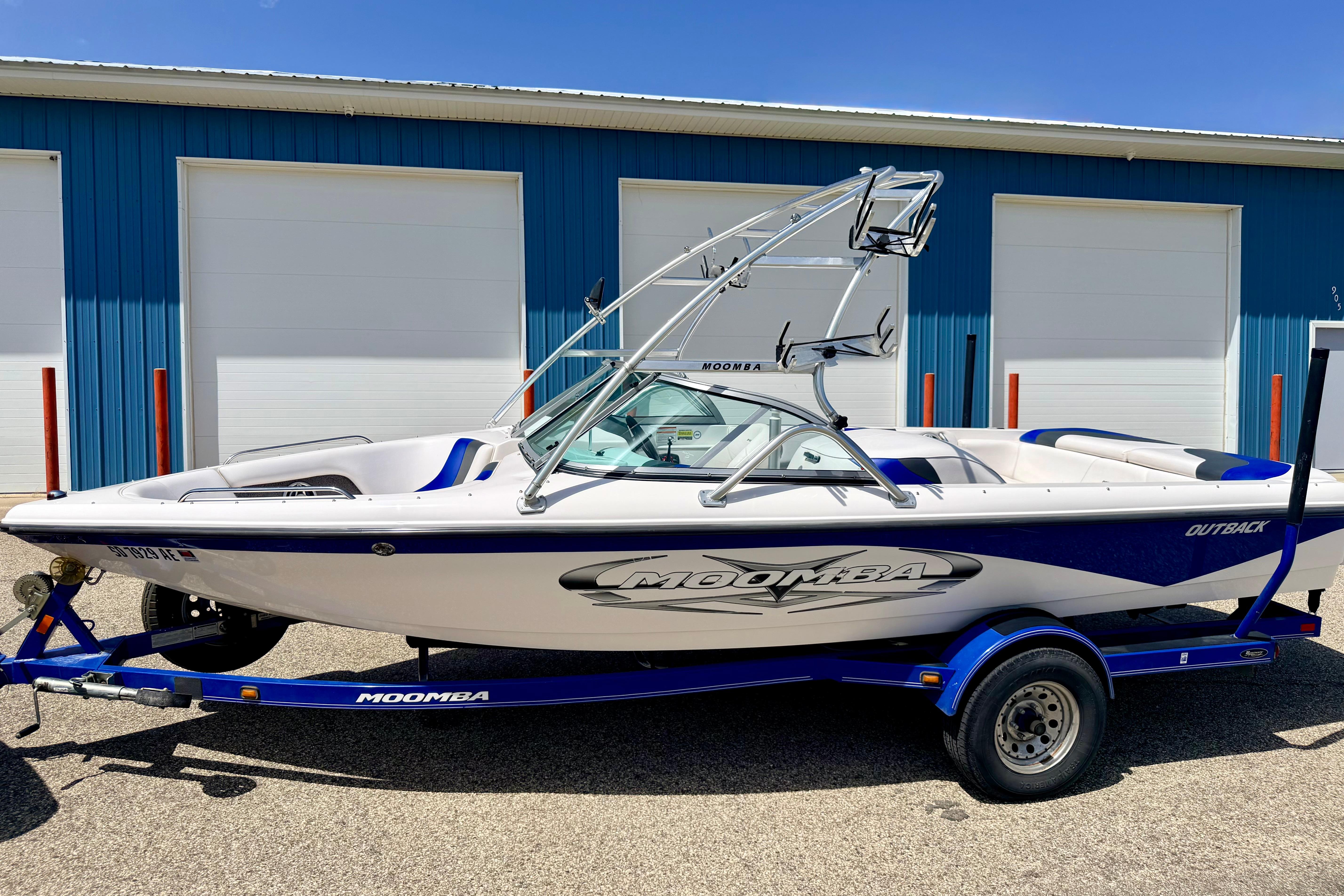 2008 Moomba Outback V boat on trailer, parked outside blue building.