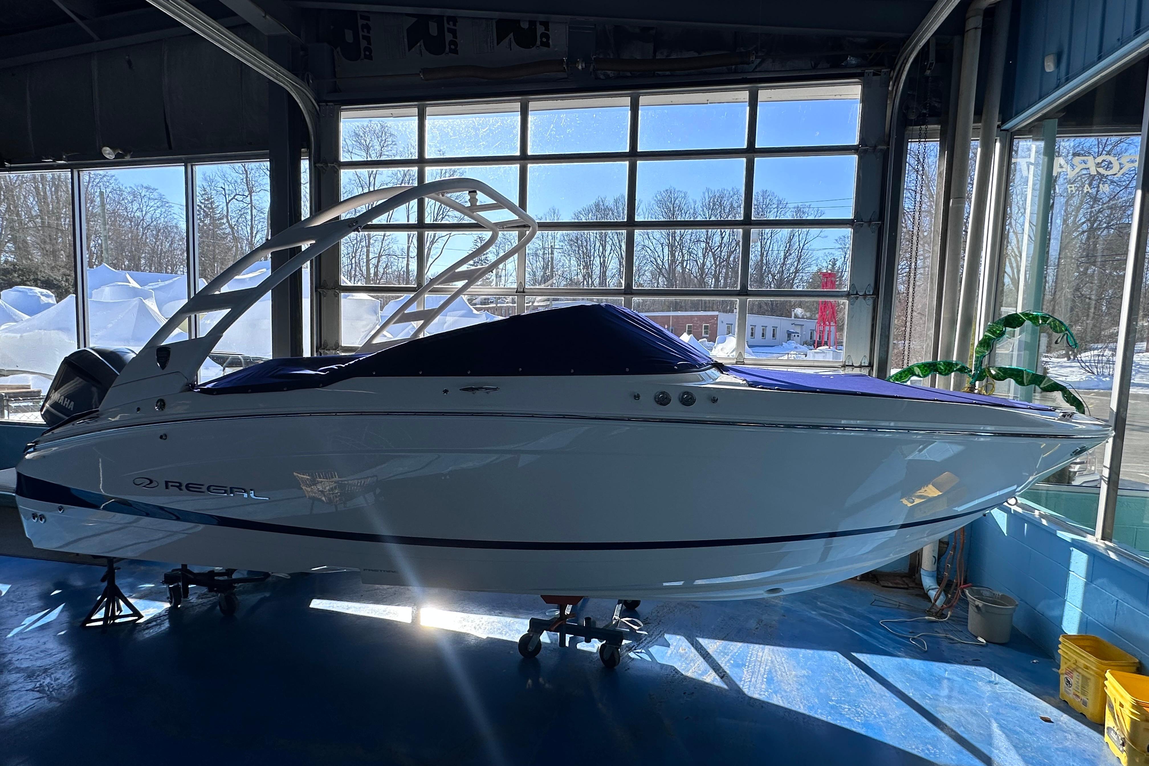 2026 Regal LX4 boat in showroom, side view with blue cover.