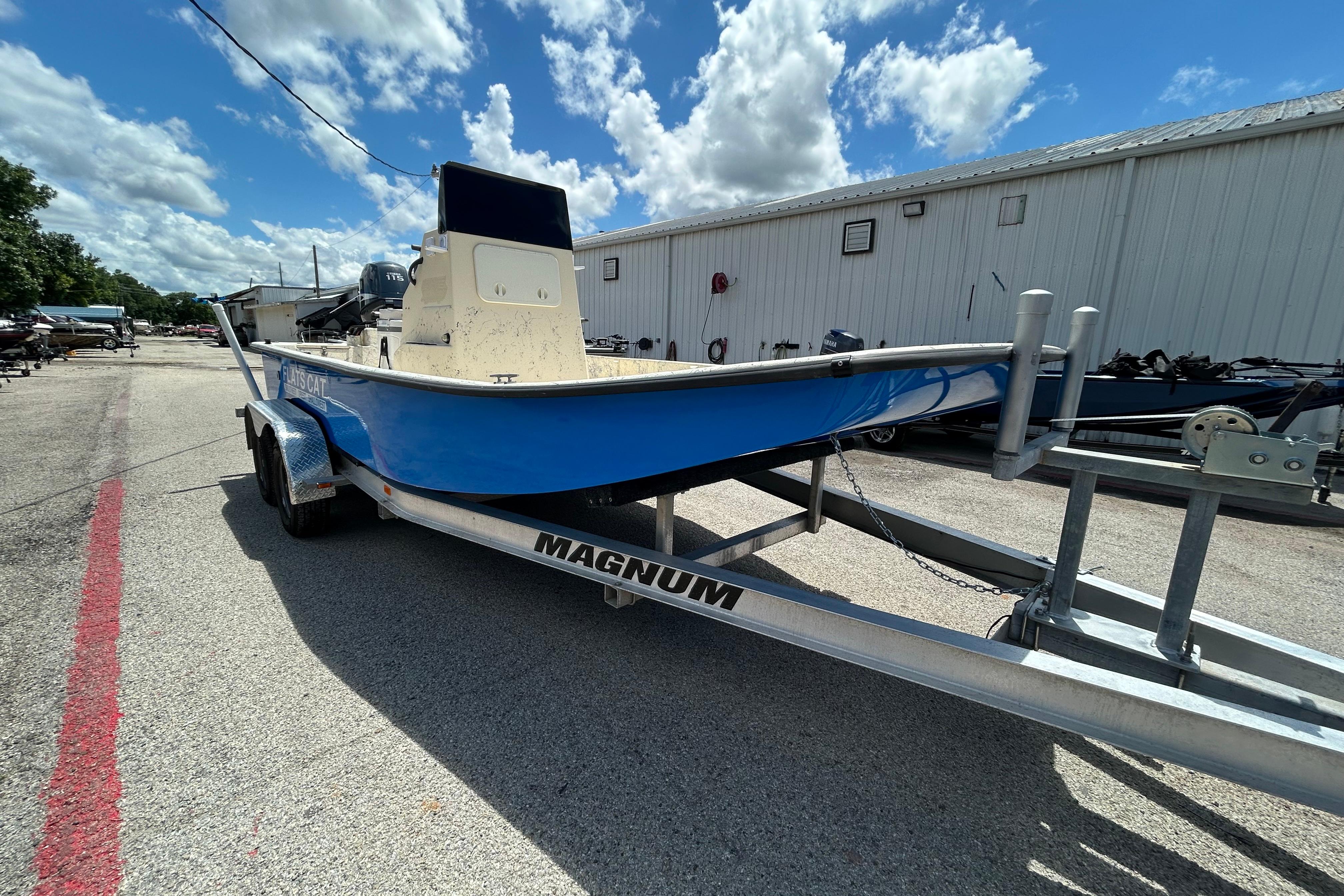 2007 Flats Cat 19 boat on trailer under a partly cloudy sky.