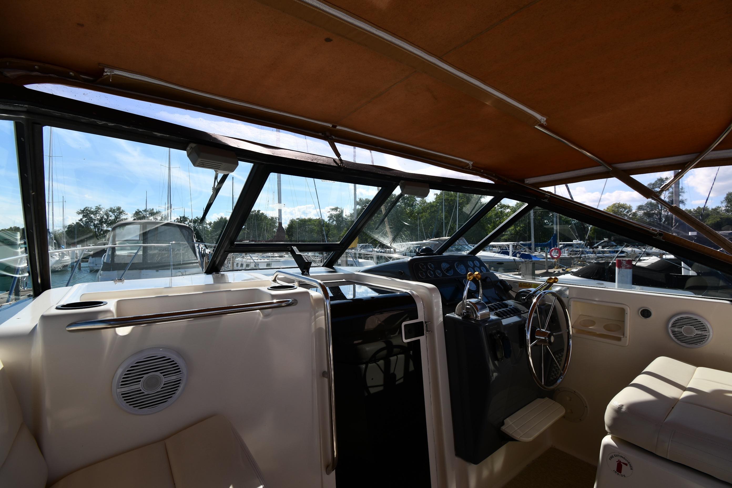 1998 Tiara Yachts 3100 Open cockpit with steering wheel and marina view.