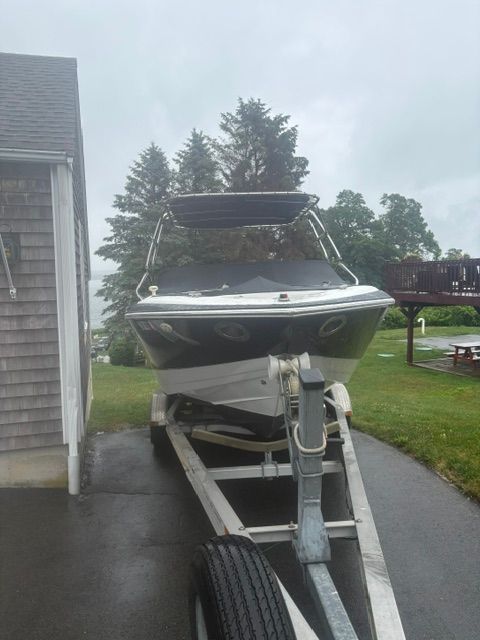 A 2003 Cobalt 240 boat is on a trailer next to a house.