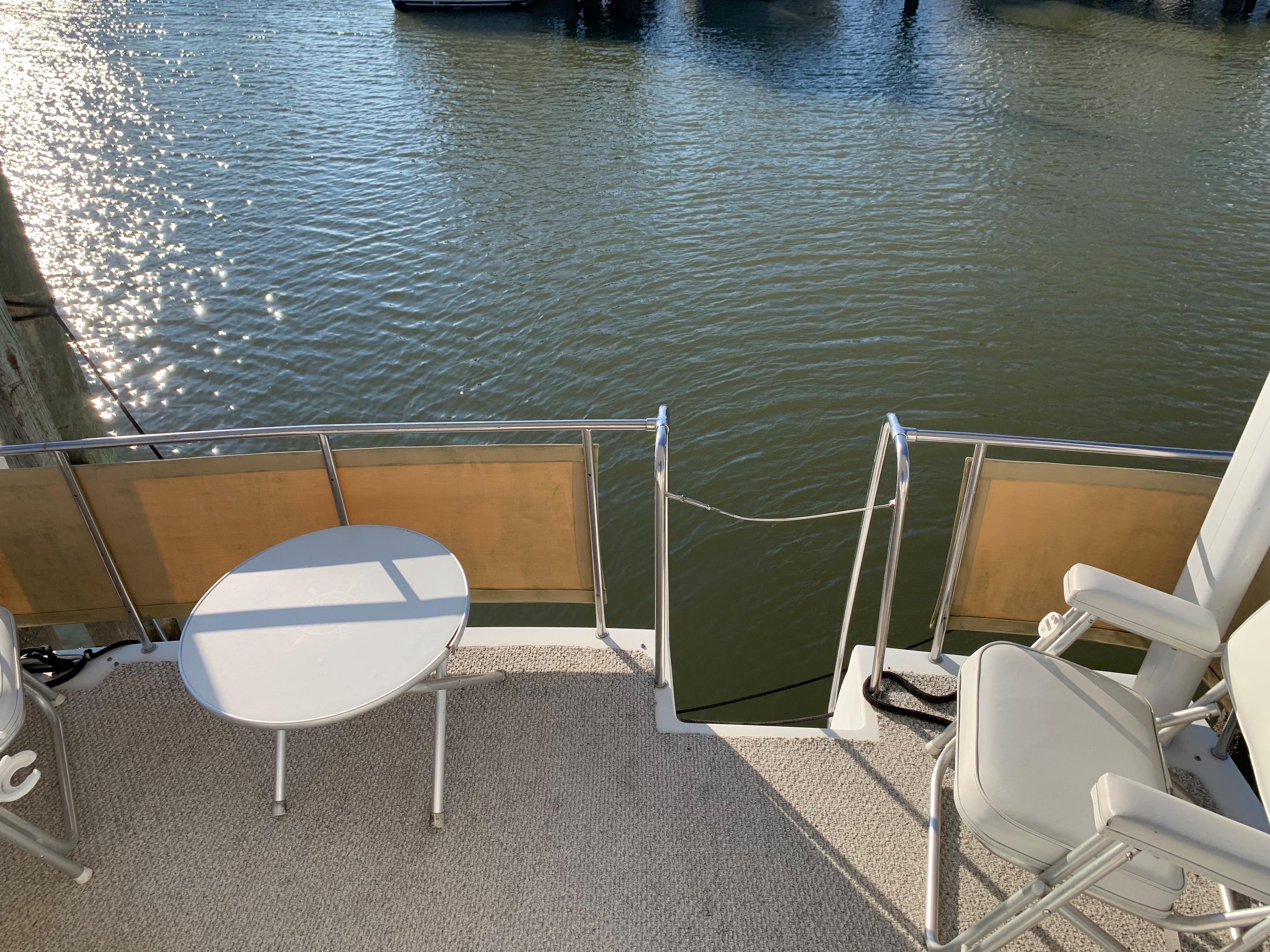 1992 Silverton 34 Aft Cabin Motor Yacht deck with chairs and table by the water.