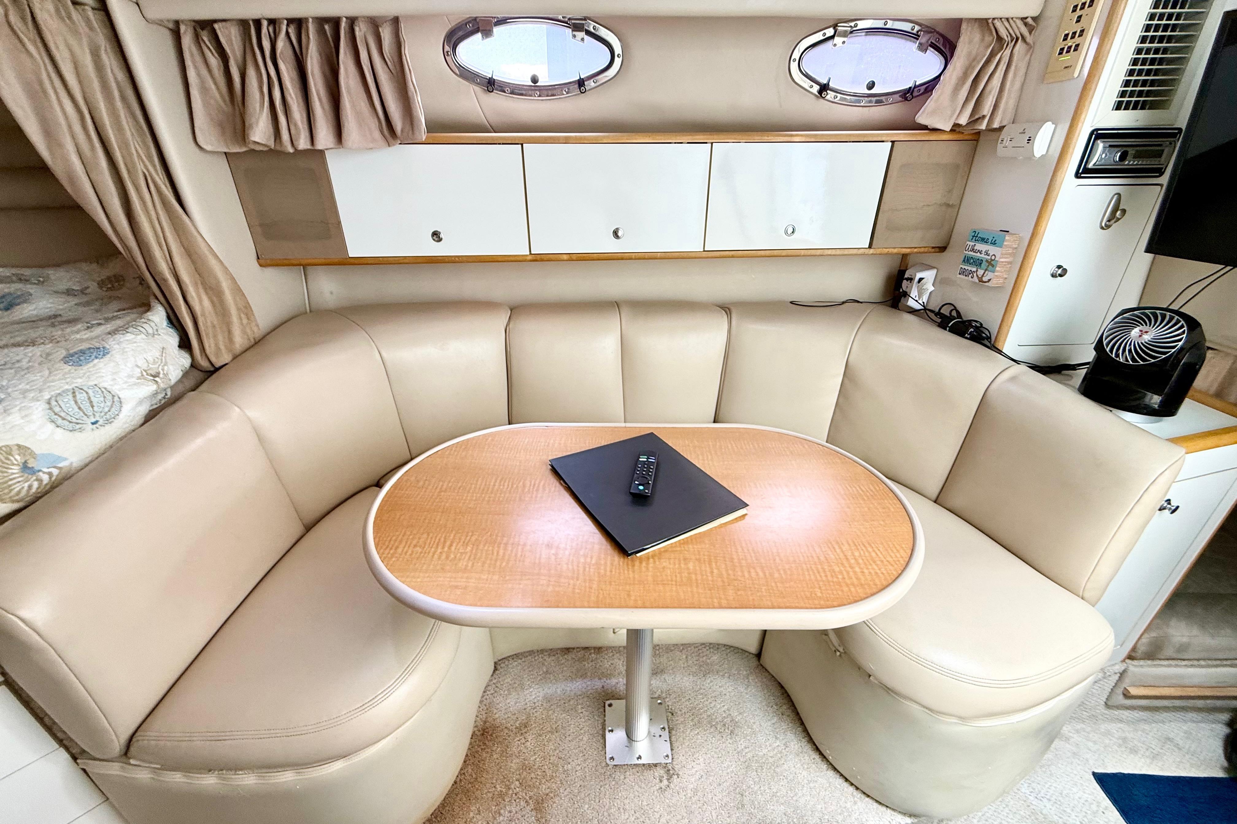 1999 Chaparral Signature 300 interior with beige seating, wooden table, and porthole windows.