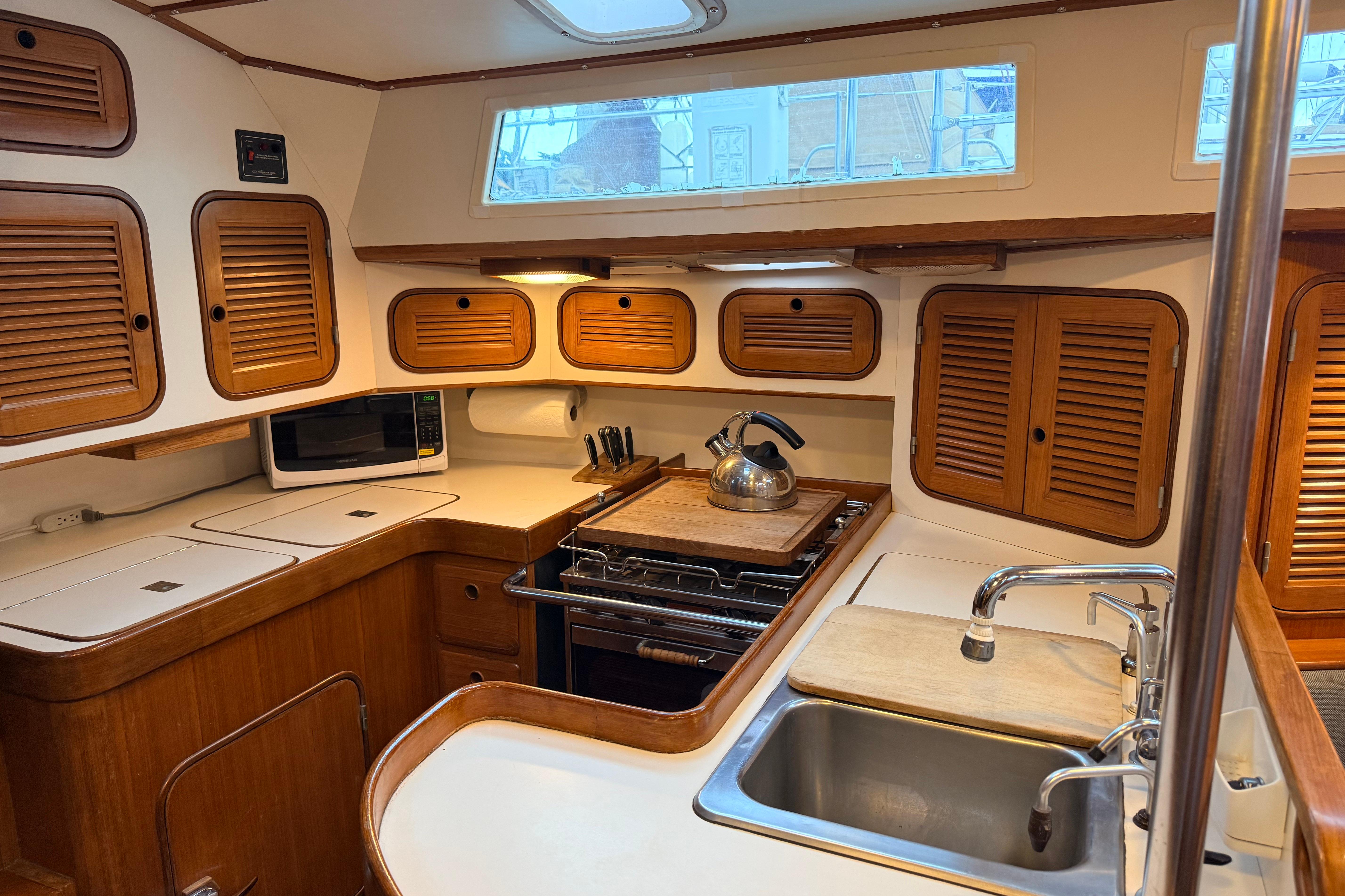 Interior of 1987 Norseman 400 sailboat kitchen with wooden cabinets and stainless steel sink.