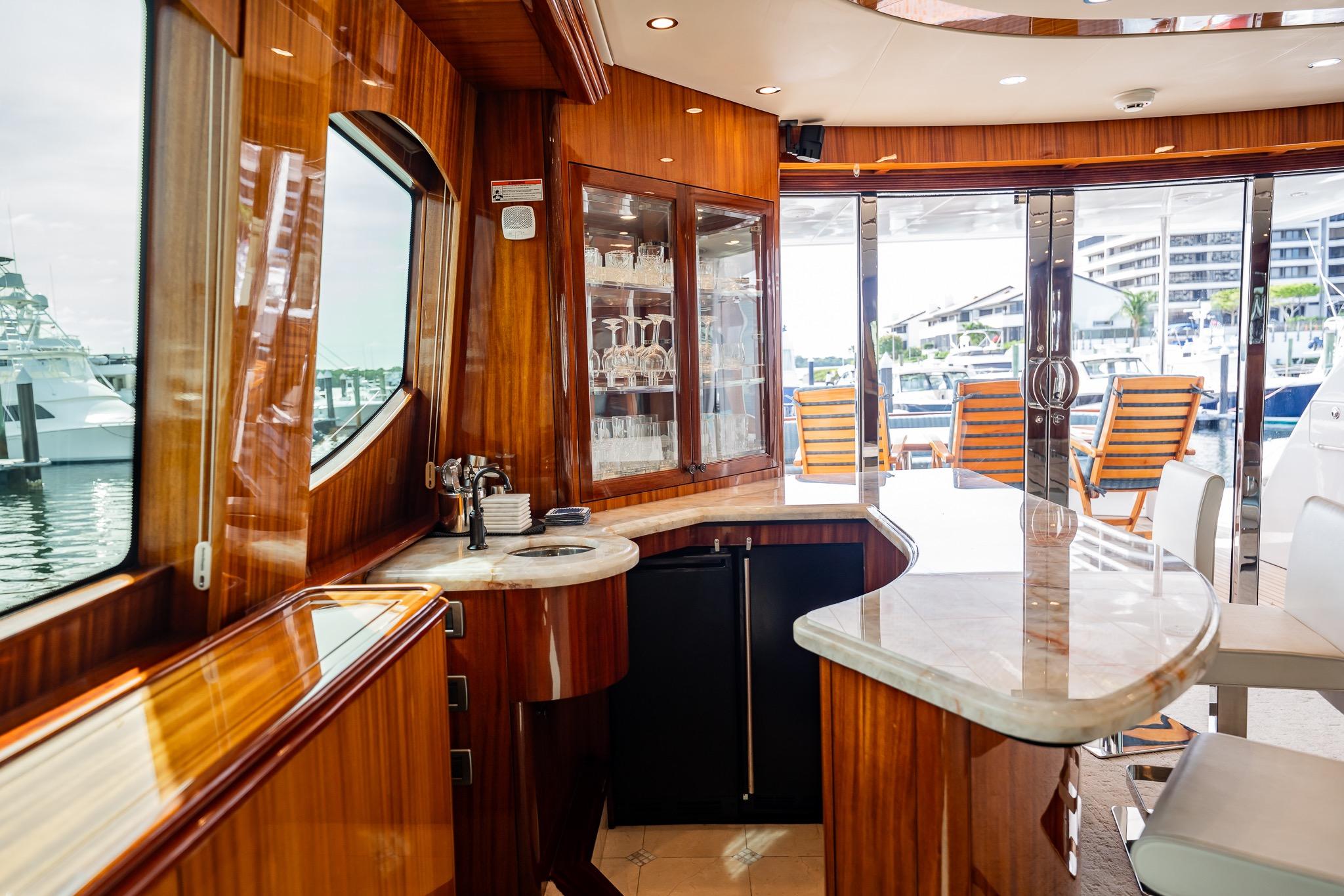 Luxurious interior of 2012 Hatteras 80 Motor Yacht with elegant bar and marina view.