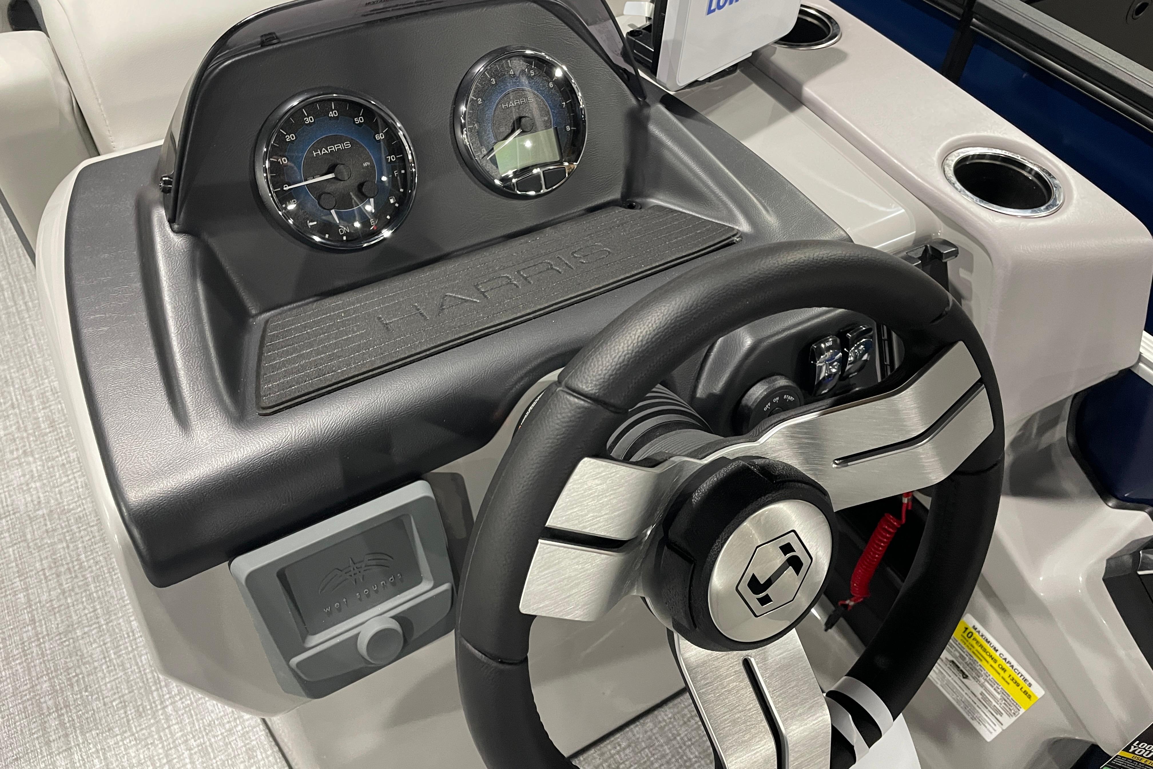 Steering console of 2026 Harris Cruiser 230 CW boat with gauges and controls.