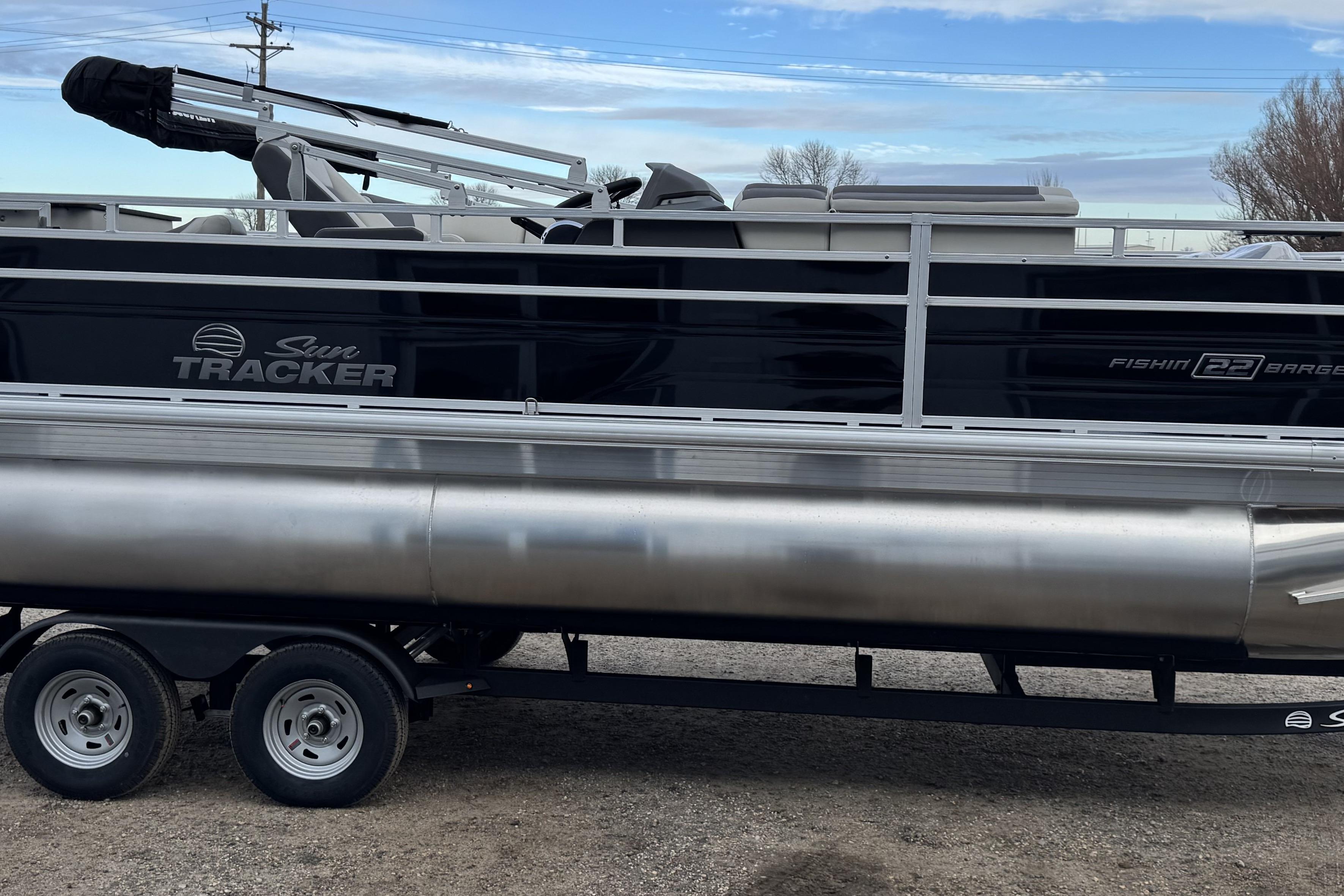 2026 Sun Tracker Fishin' Barge 22 DLX pontoon boat on trailer, side view.