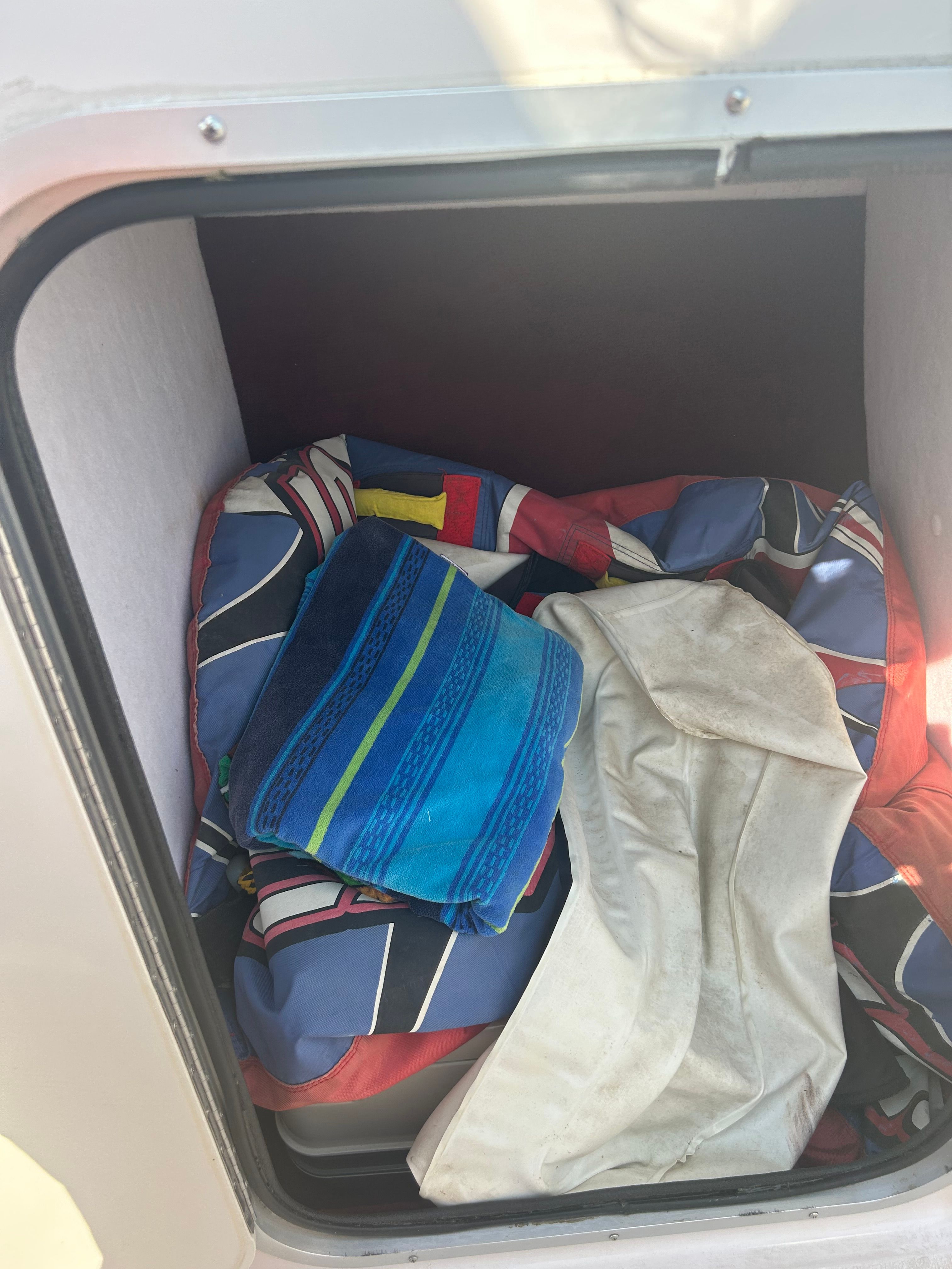 A storage compartment with colorful blankets and towels on a boat.