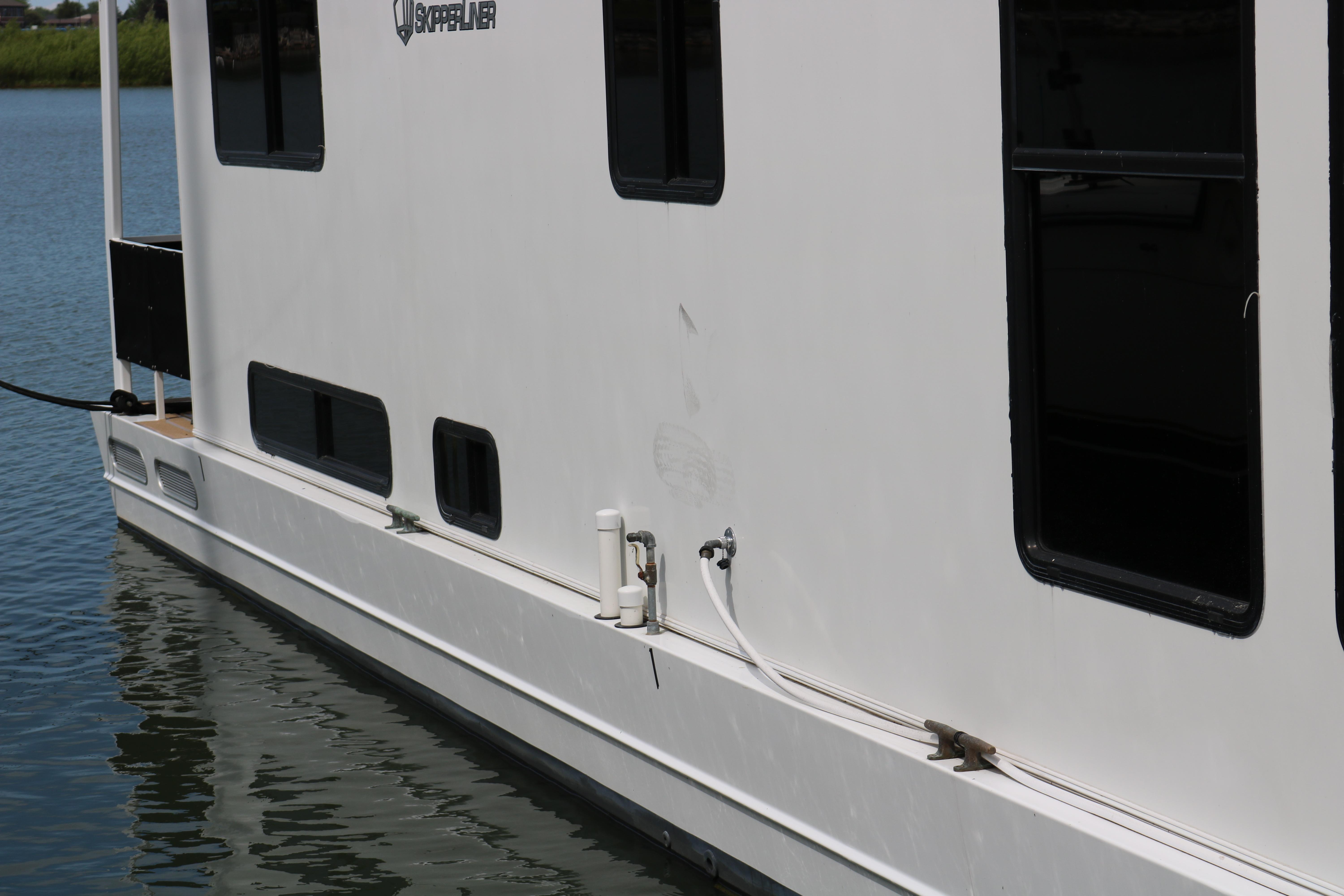 Skipperliner 480 Flybridge 2010 houseboat side view on calm water.