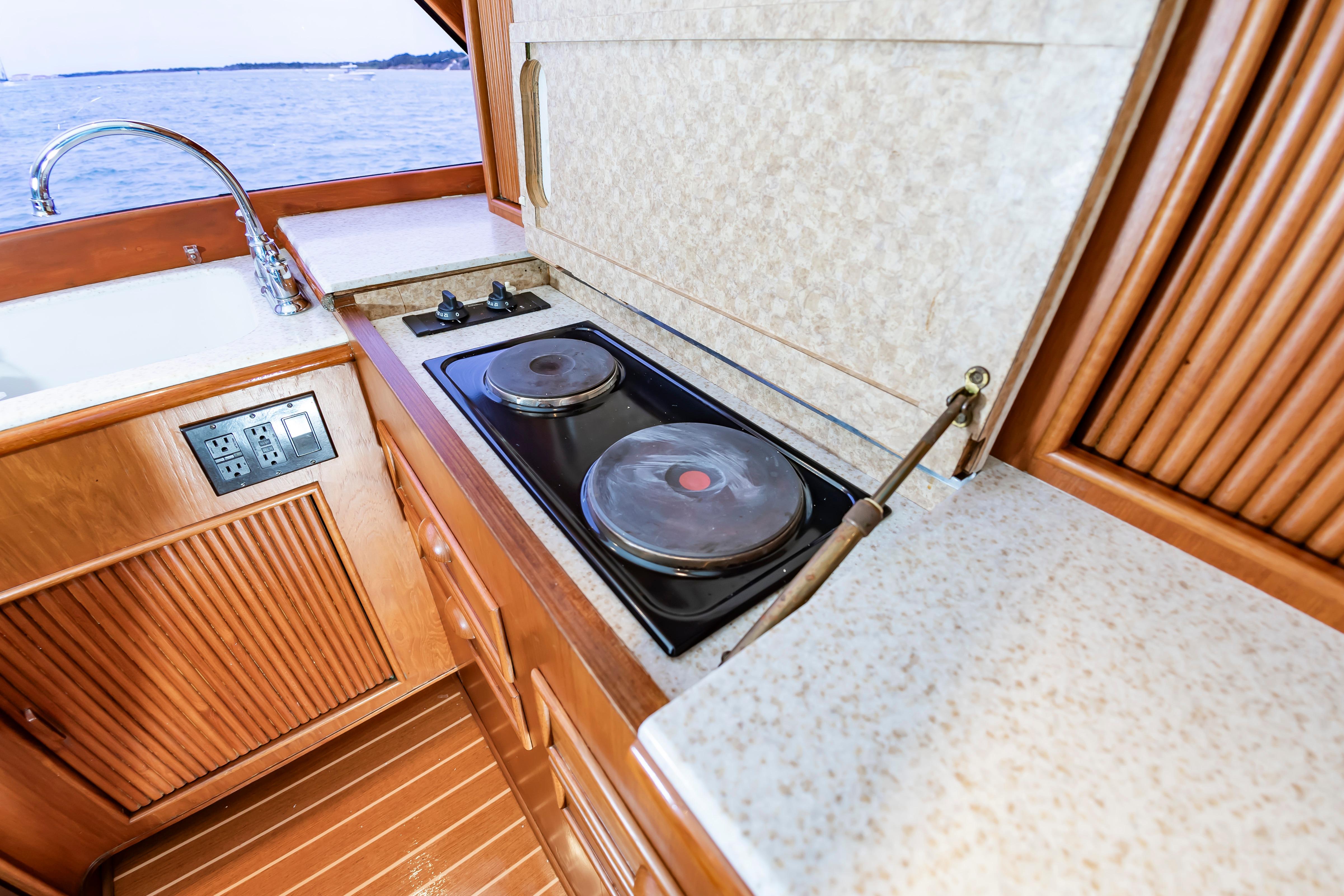 Kitchen area of 1993 Custom Carolina Scarborough 56 Convertible yacht with stove and sink.
