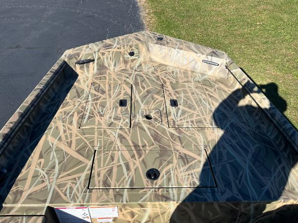 2025 Lowe Roughneck 1760 boat with camouflage pattern on grass and pavement.