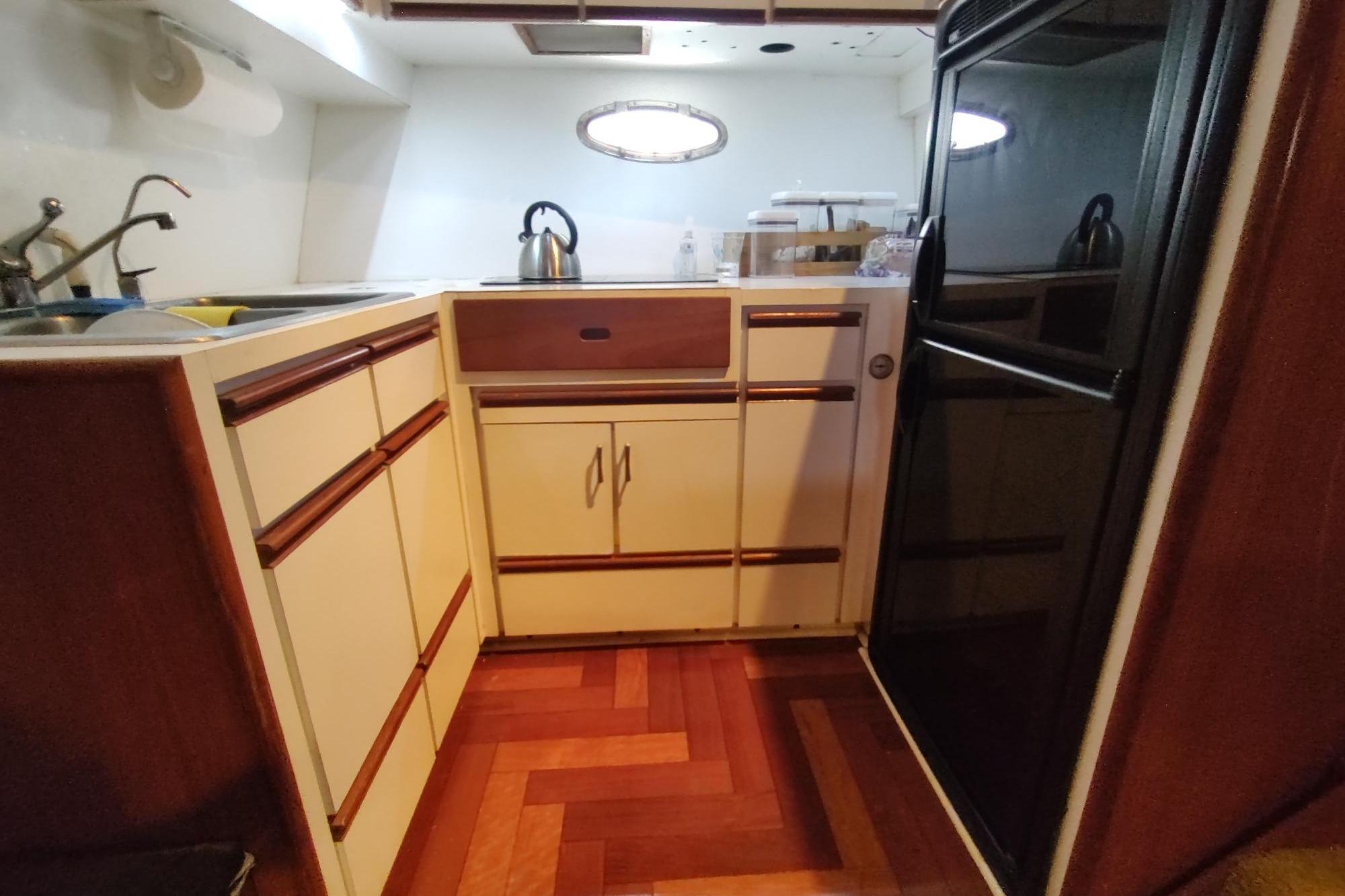 Compact kitchen in 1989 Hyatt Double Cabin Motoryacht with wood accents and modern appliances.