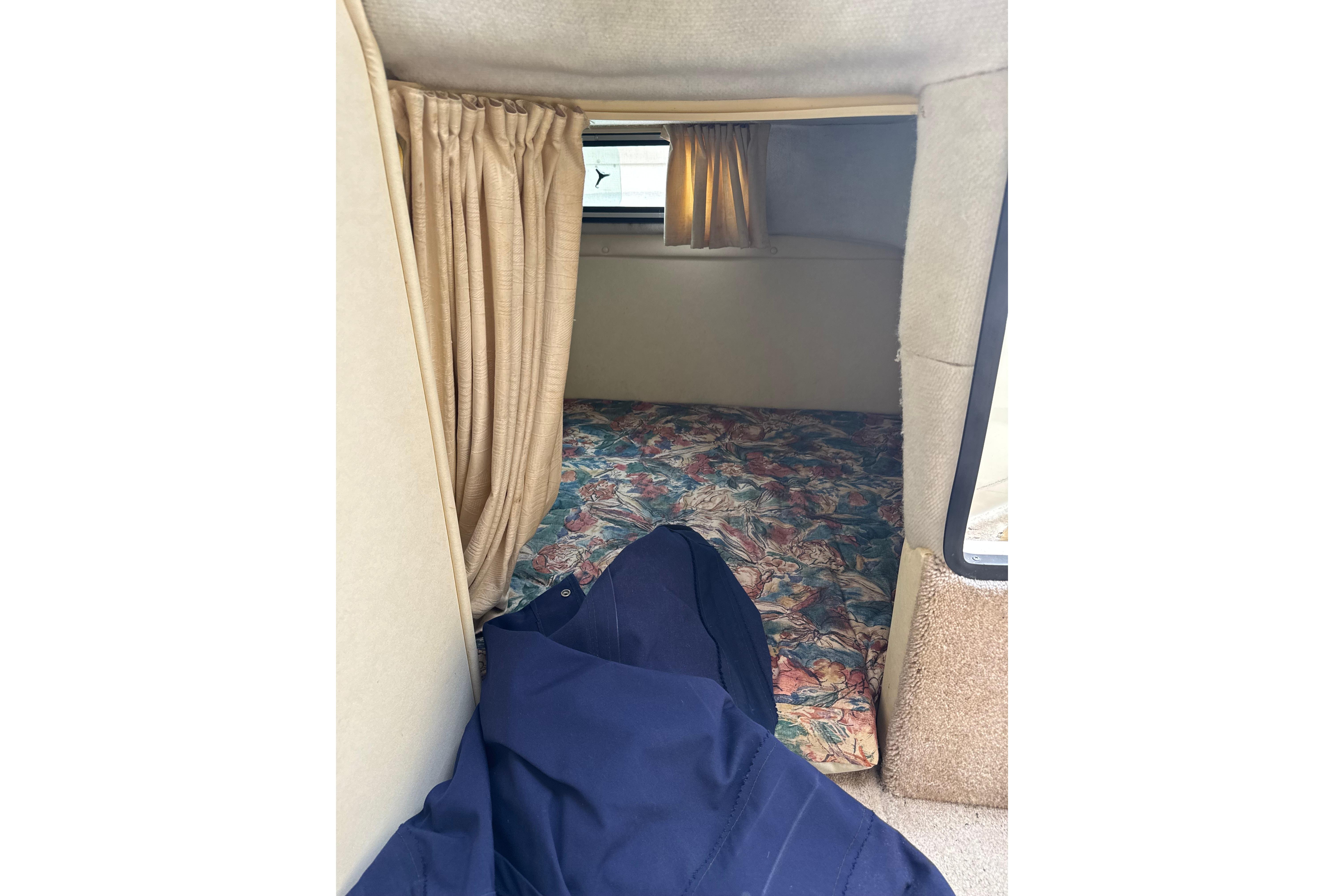 Interior cabin of a 1997 Monterey 256 Cruiser with floral bedding and curtains.