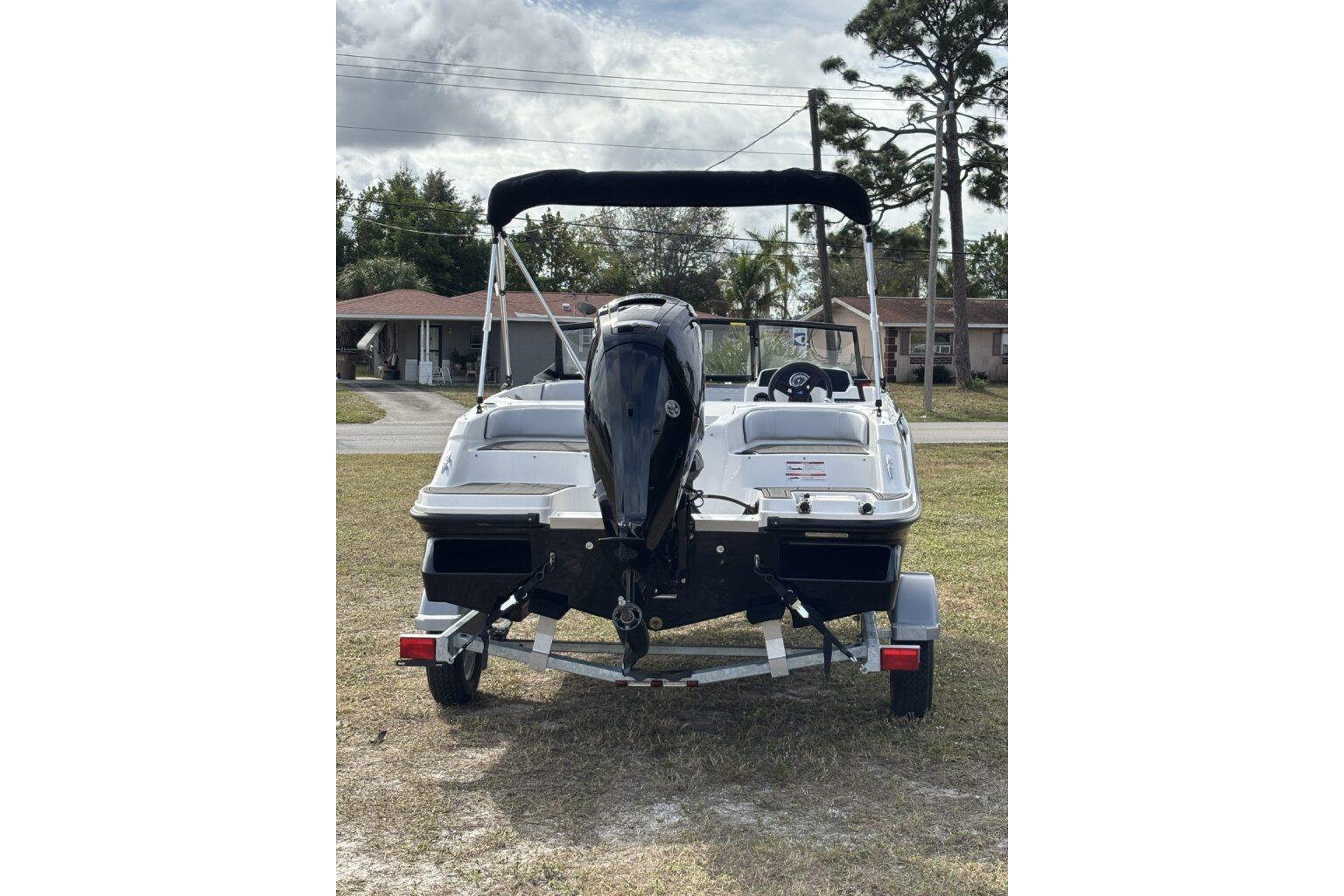 2025 Bayliner Element M17 boat on trailer, rear view, parked on grass.