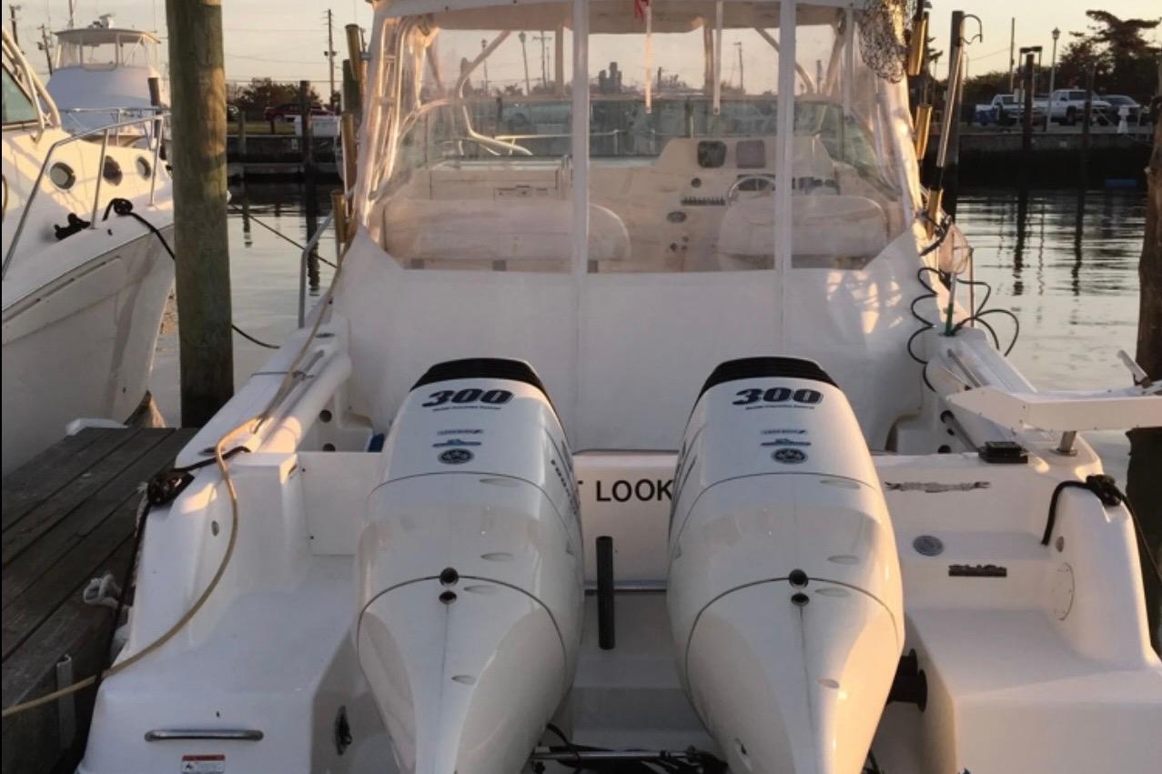 2004 Wellcraft 290 Coastal boat with twin 300 horsepower engines docked at marina.