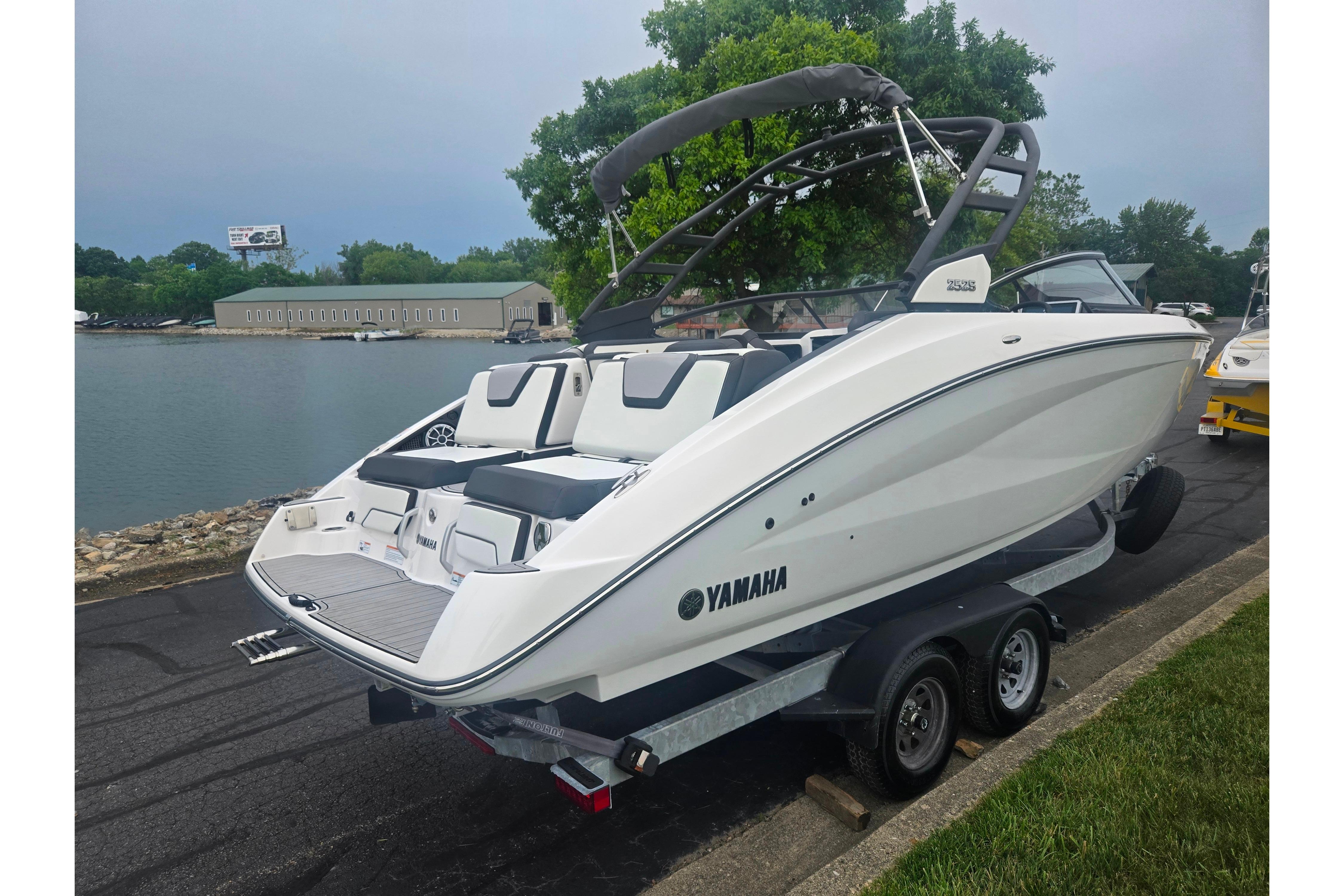 2023 Yamaha Boats 252S on trailer by waterfront, showcasing sleek design and modern features.