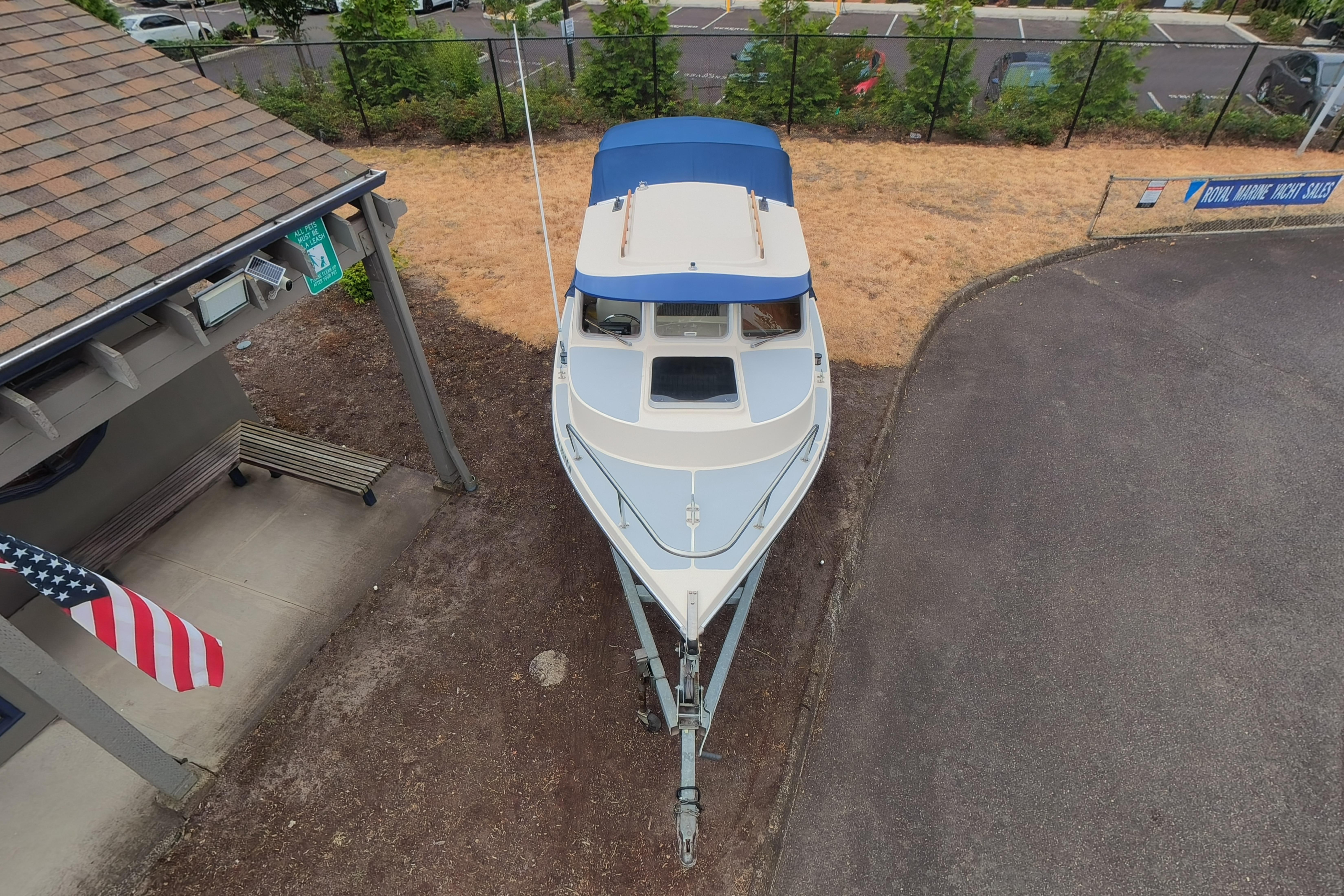 1989 C-Dory 22' Angler boat on trailer, aerial view near building and American flag.