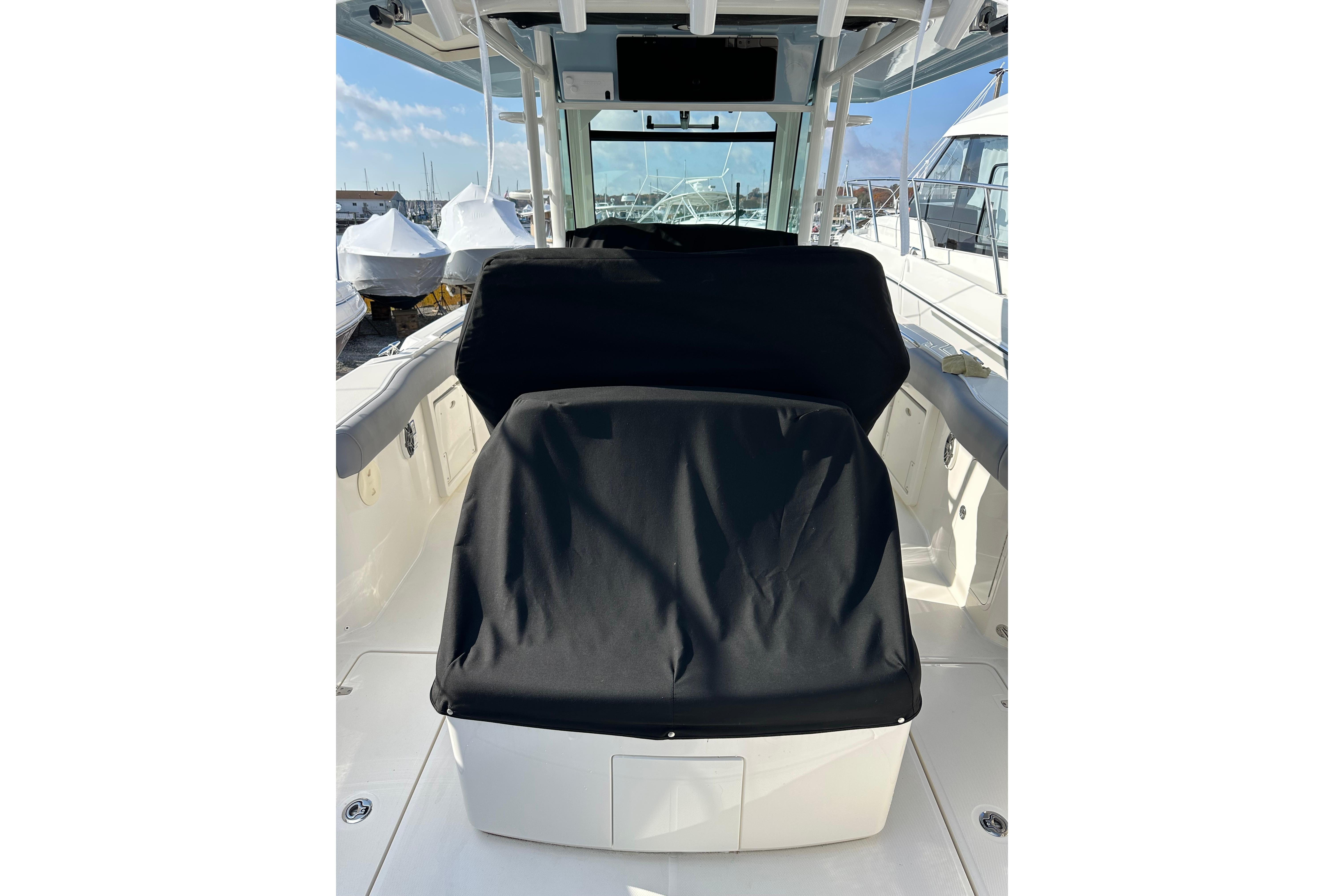 2023 Boston Whaler 330 Outrage boat interior with covered seating, docked at marina.